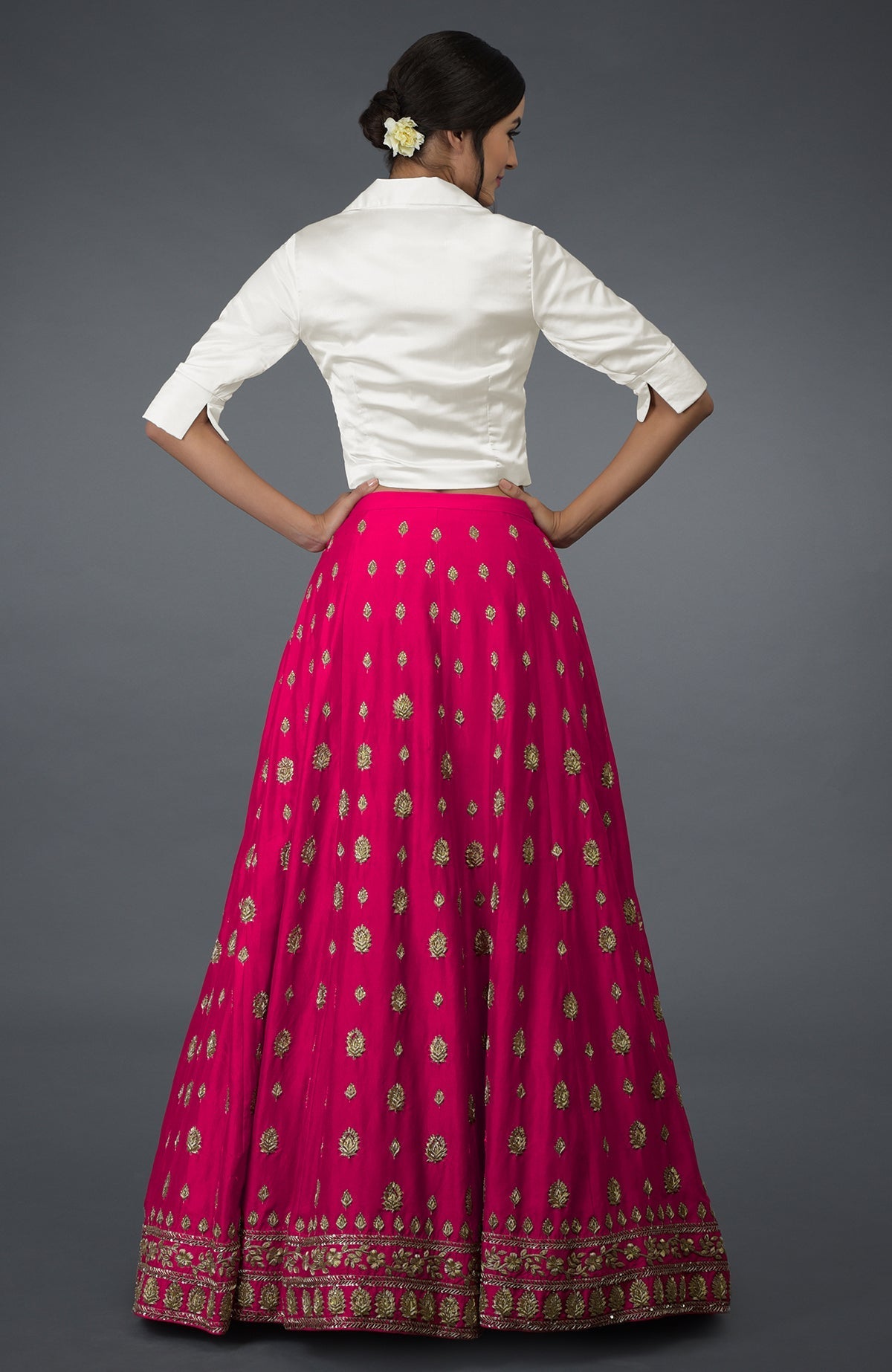 A woman models a berry gloss silk skirt with gold embroidery and a white blouse.
