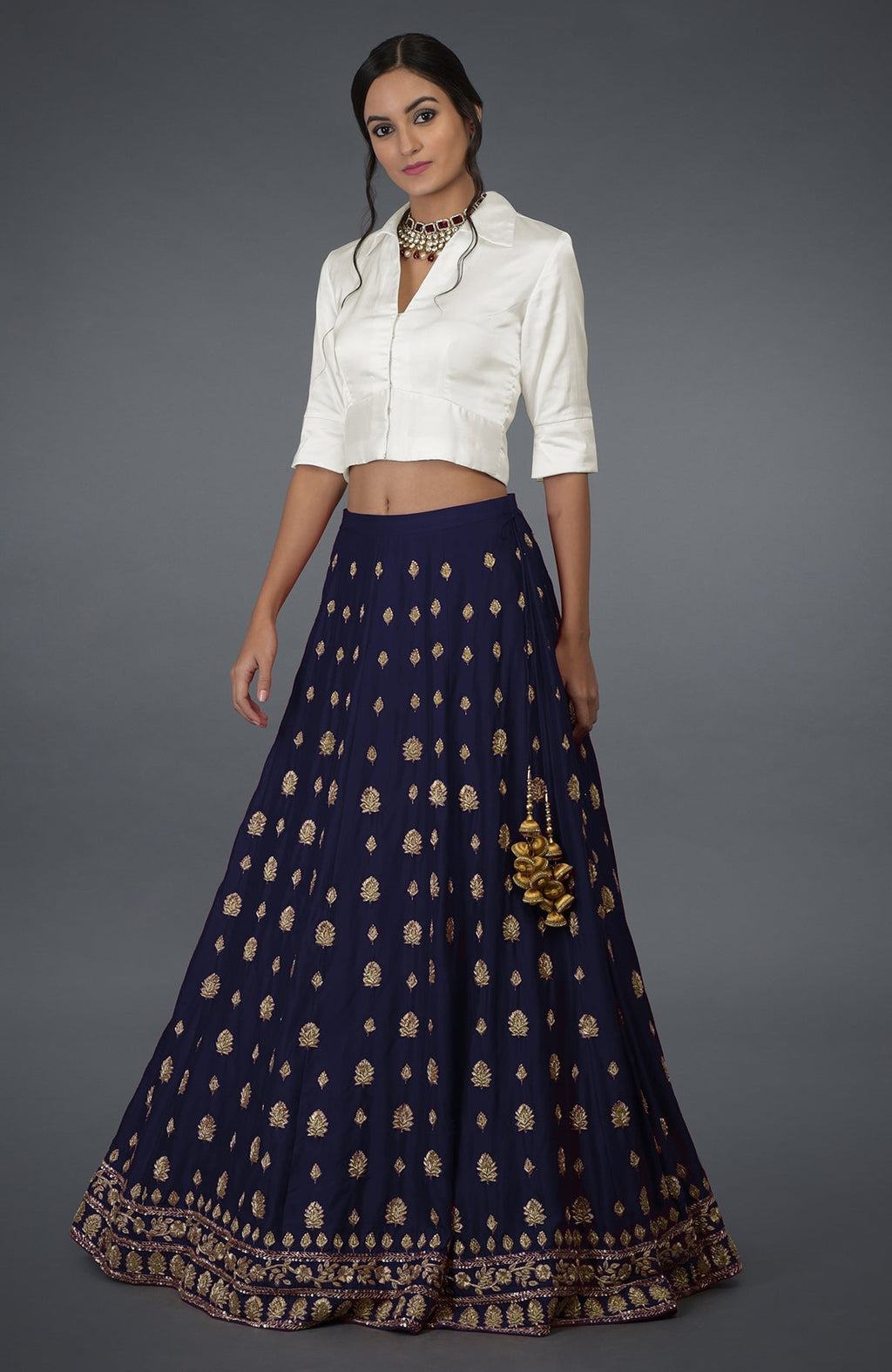 A woman models an eclipse blue zardozi and crystal hand-embroidered skirt with a white crop top.