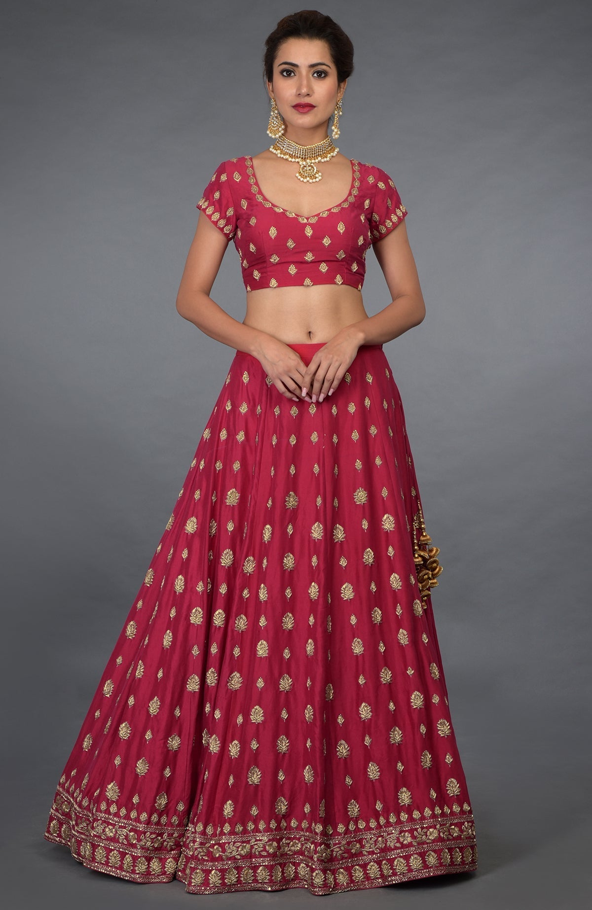 A woman models a royal red Zardozi and crystal hand-embroidered lehenga outfit.