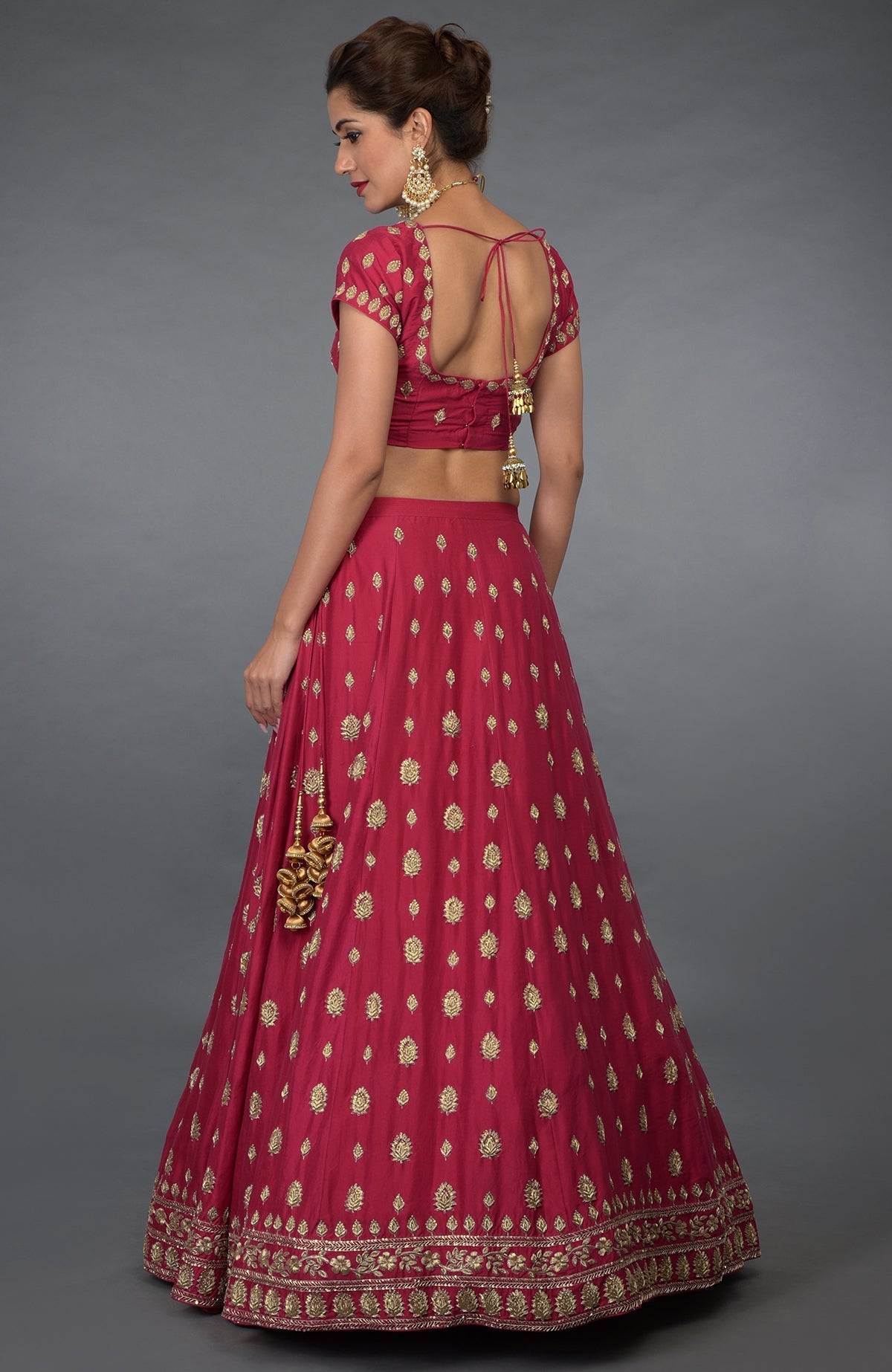 A woman models a red Zardozi and crystal hand-embroidered lehenga outfit.