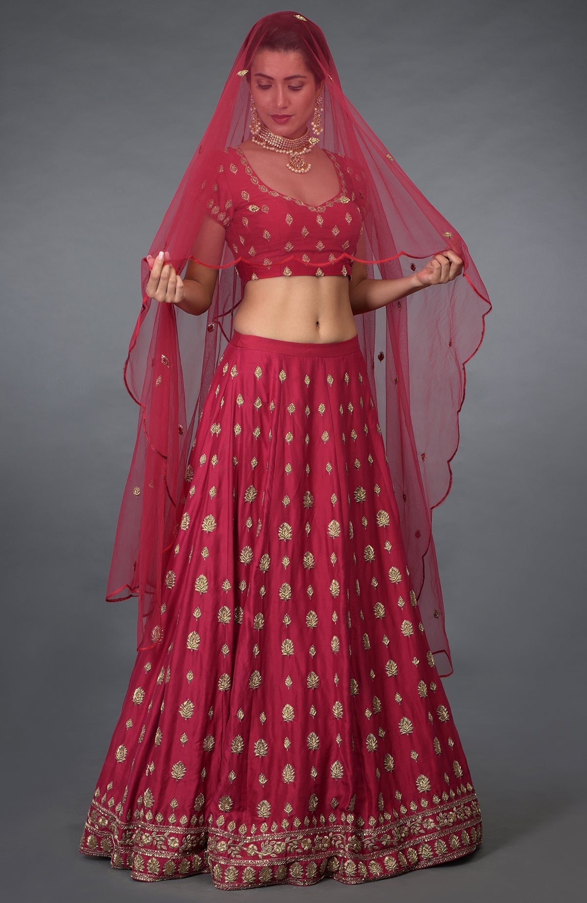 A woman models a red Zardozi and crystal hand-embroidered lehenga outfit.