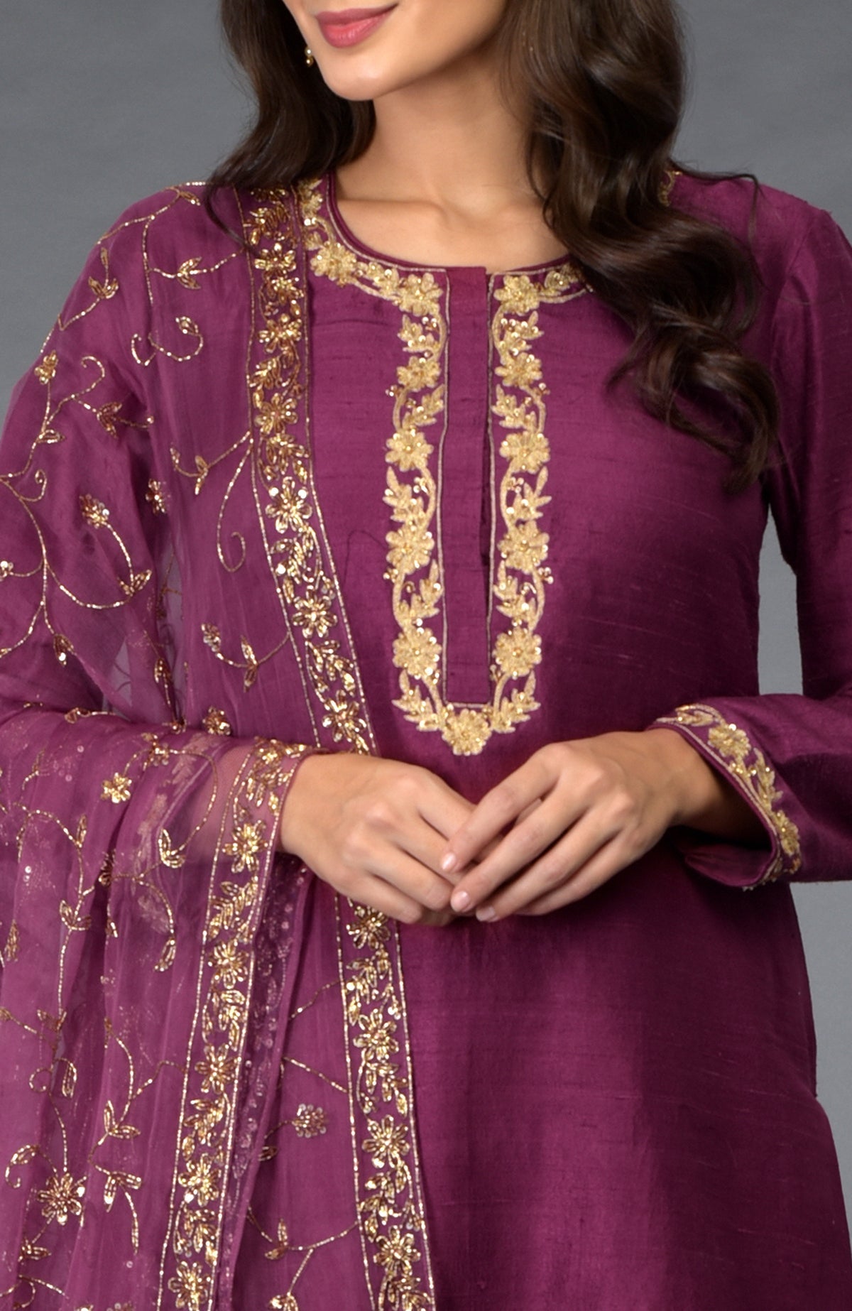 A woman models a peacock pink suit with gold zari, beads, and sequin embroidery.