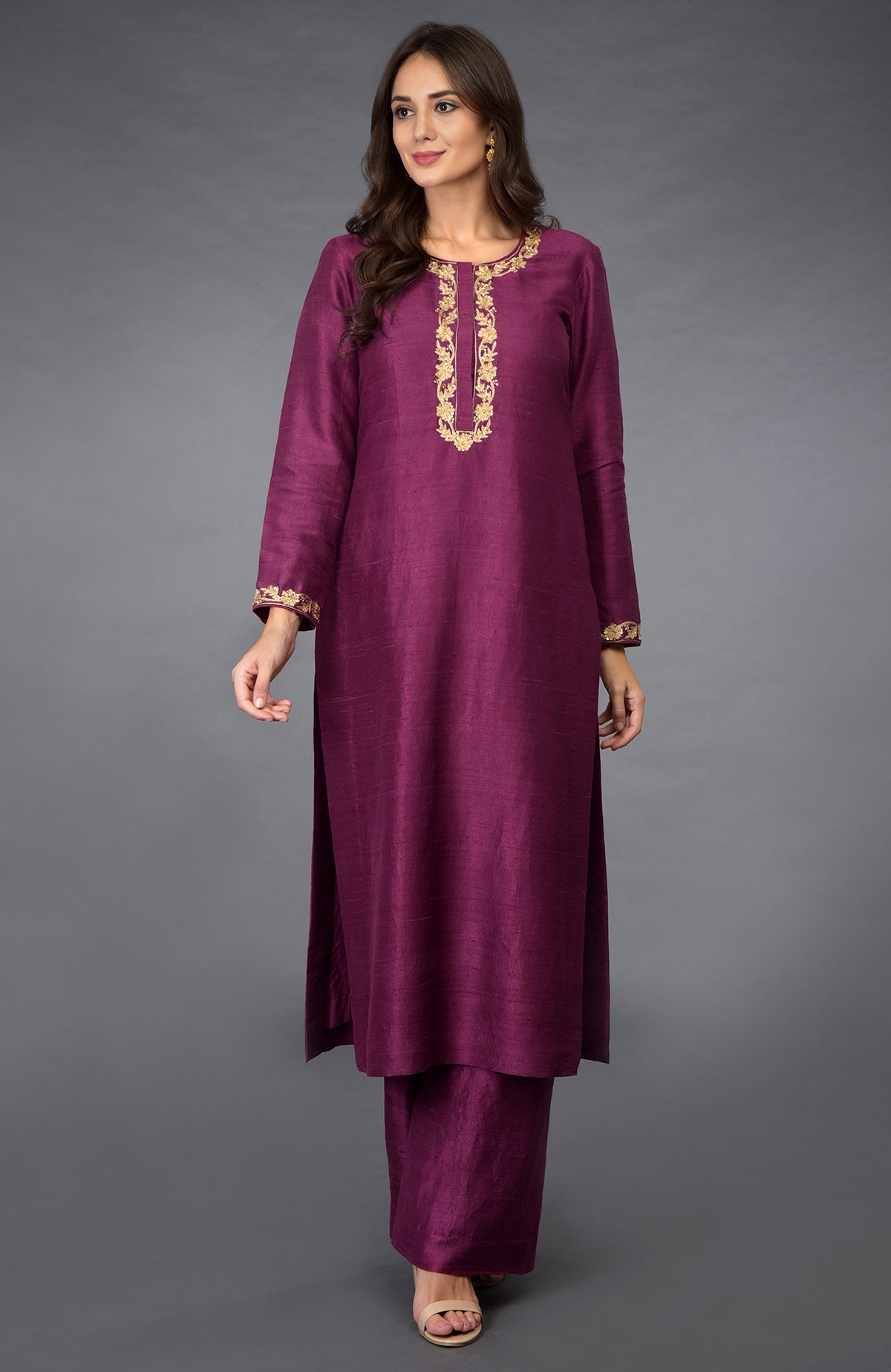 A woman models a peacock pink suit with gold zari, beads, and sequin embroidery.