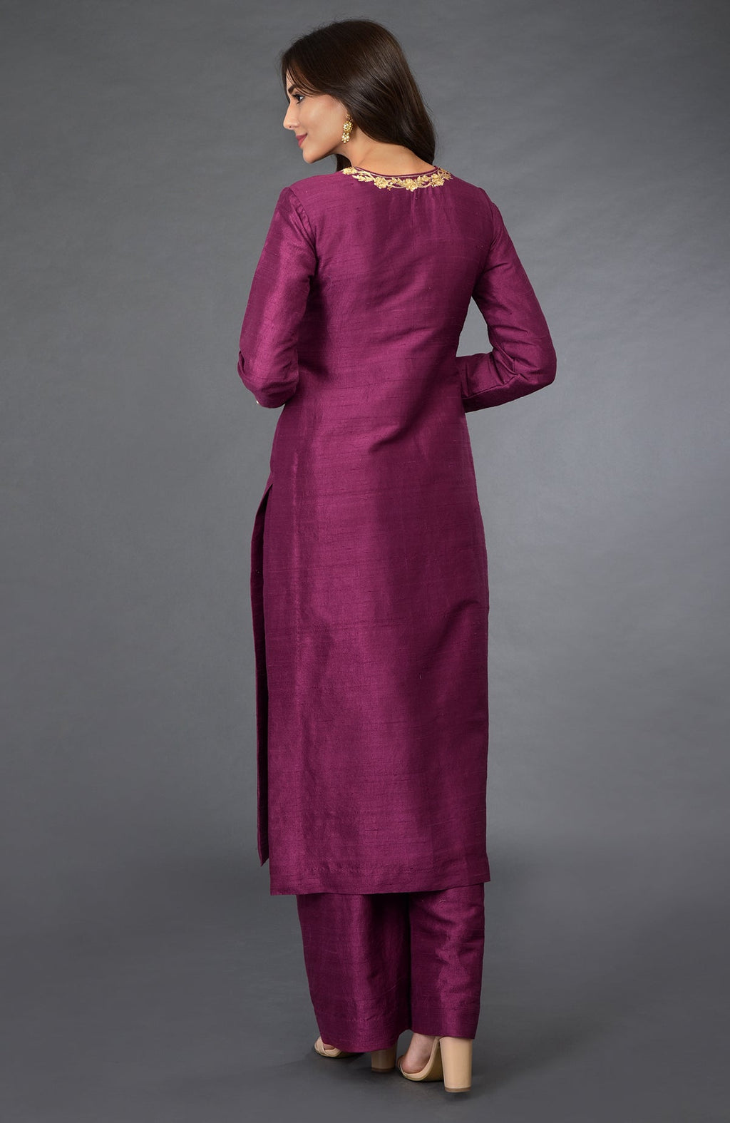 A woman models a peacock pink suit with gold zari and sequin embroidery.