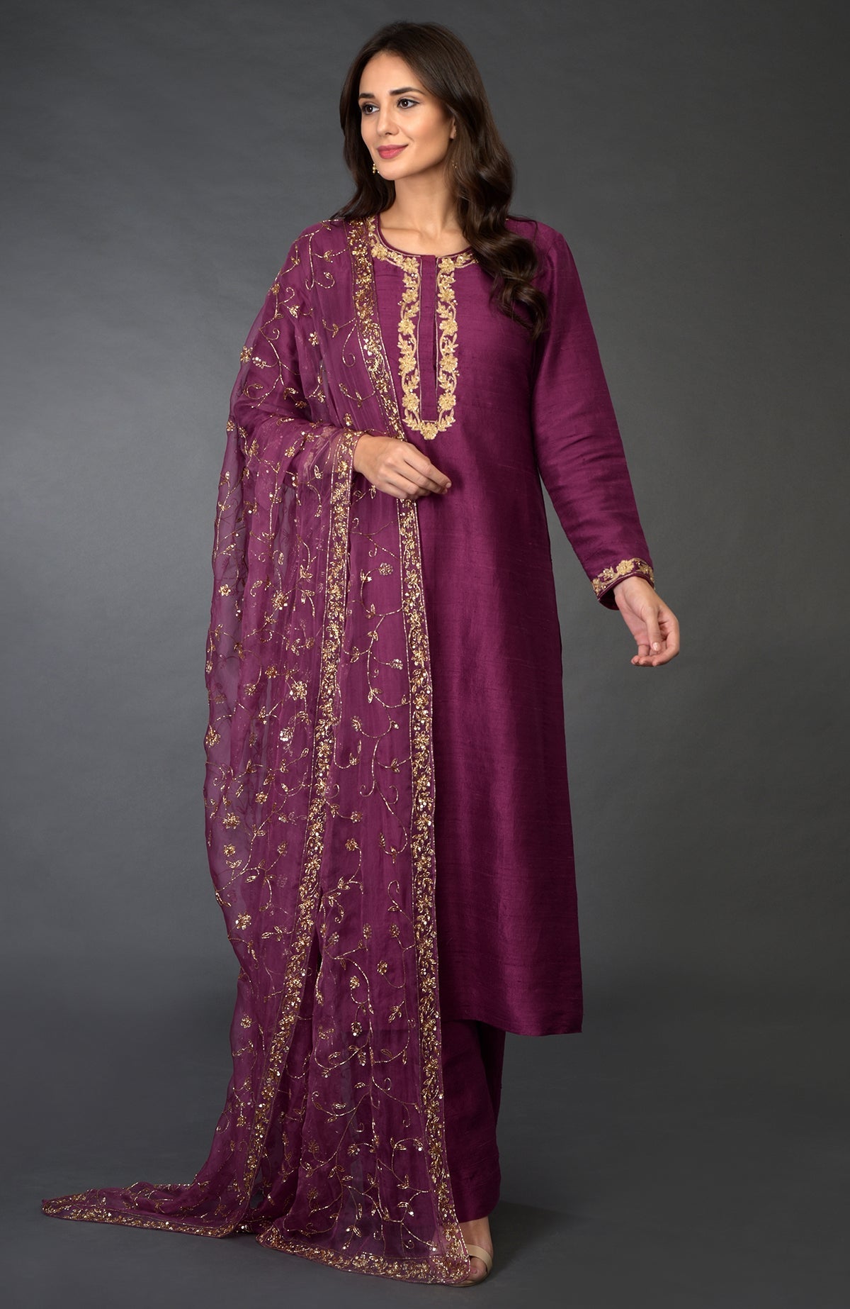 A woman models a peacock pink suit with gold zari, beads, and sequin embroidery.