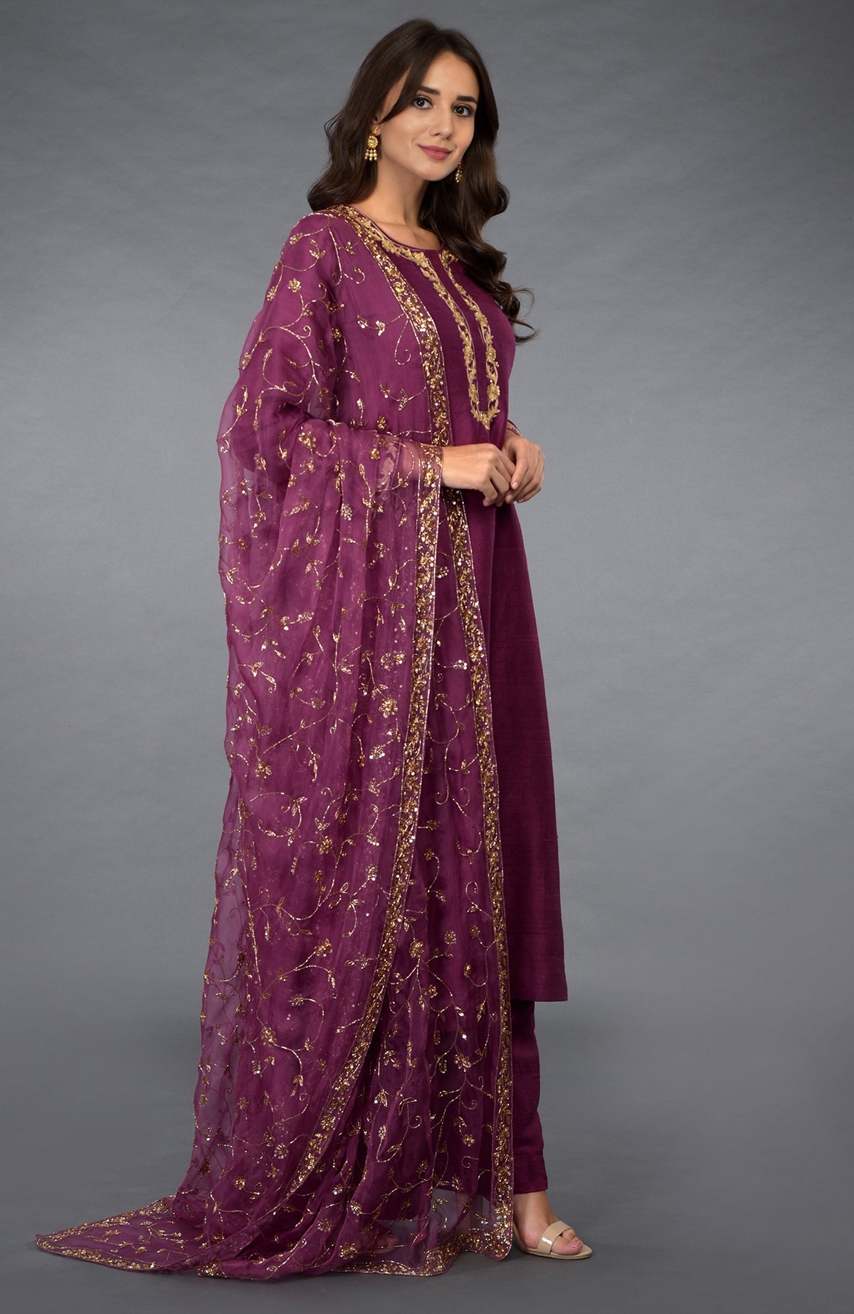 A woman models a peacock pink suit with gold zari, beads, and sequin embroidery.