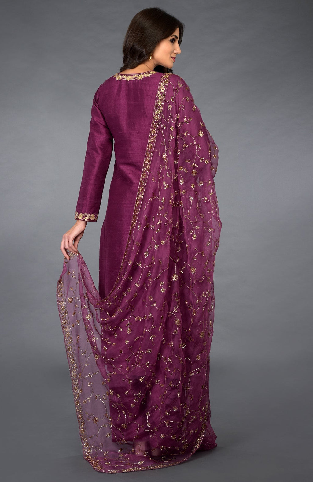 A woman models a peacock pink suit with gold zari, beads, and sequin embroidery.