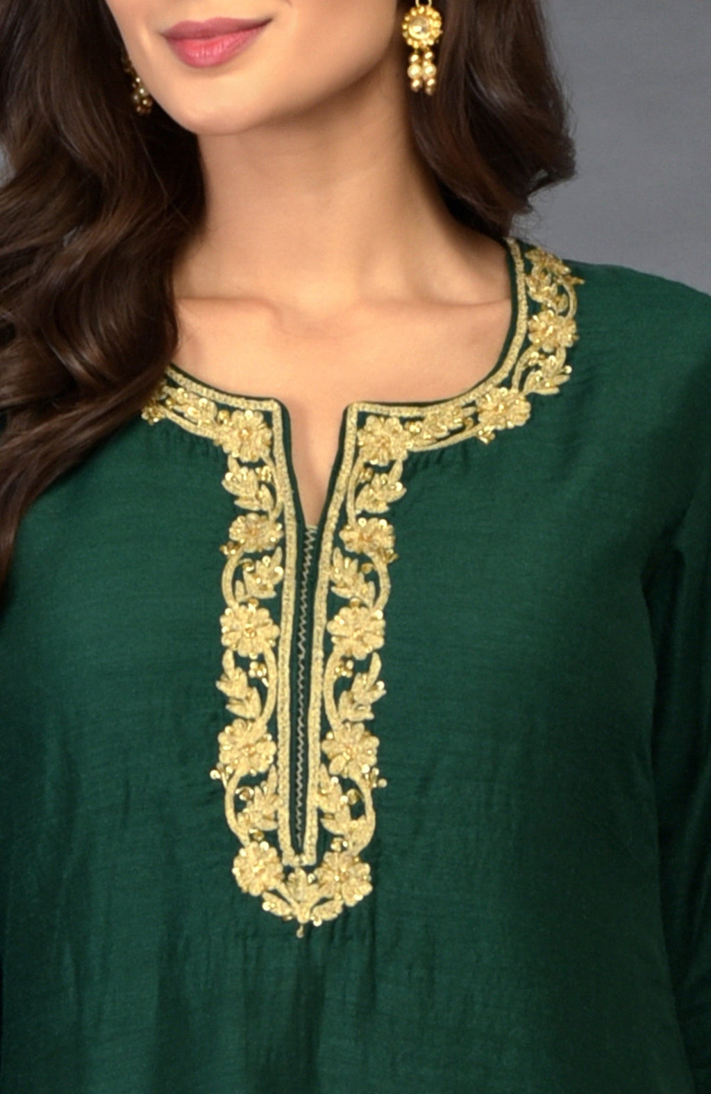 Emerald green suit with gold zari, beads, and sequin embroidery around the neckline.