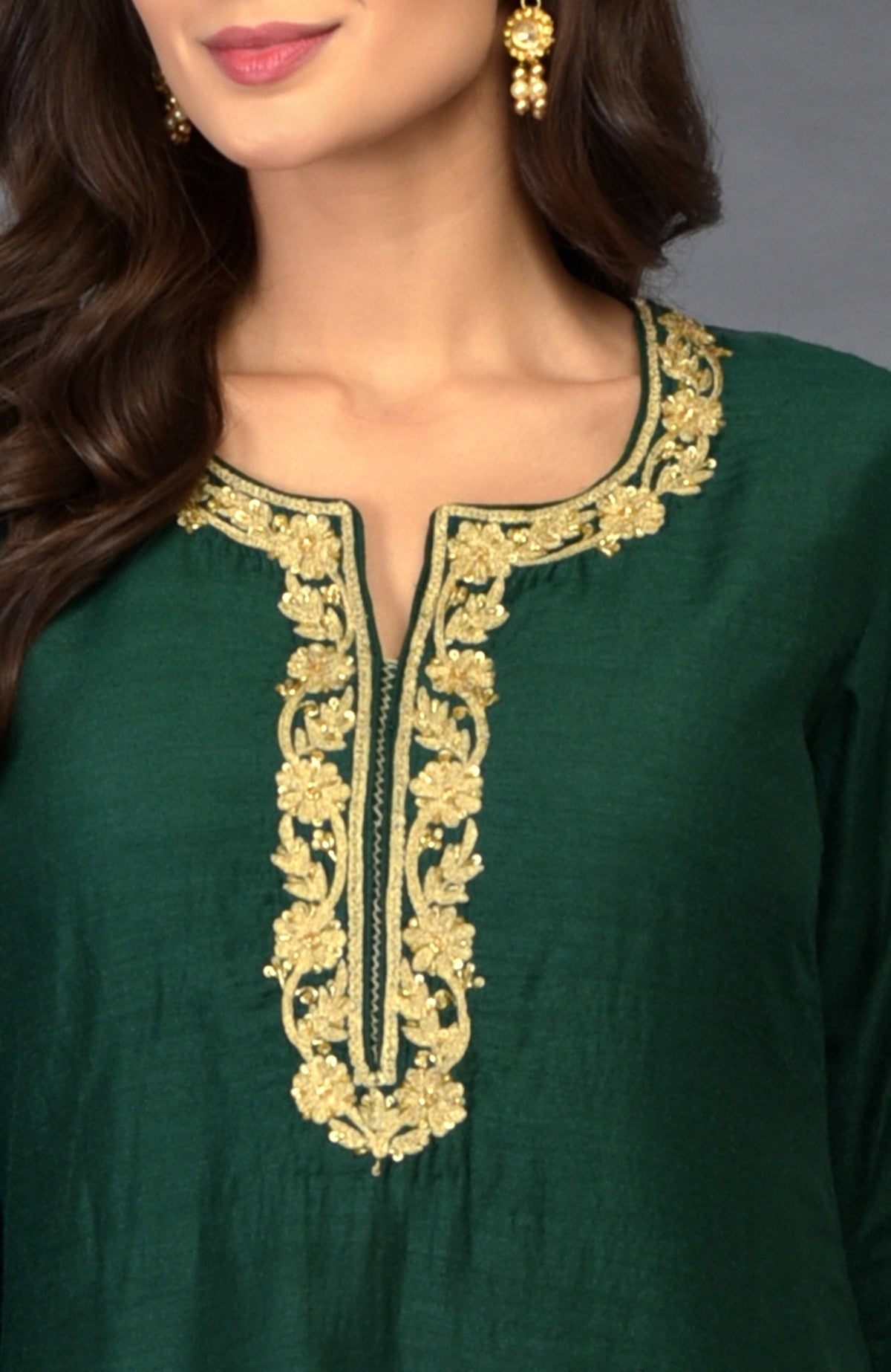 Emerald green suit with gold zari, beads, and sequin embroidery around the neckline.
