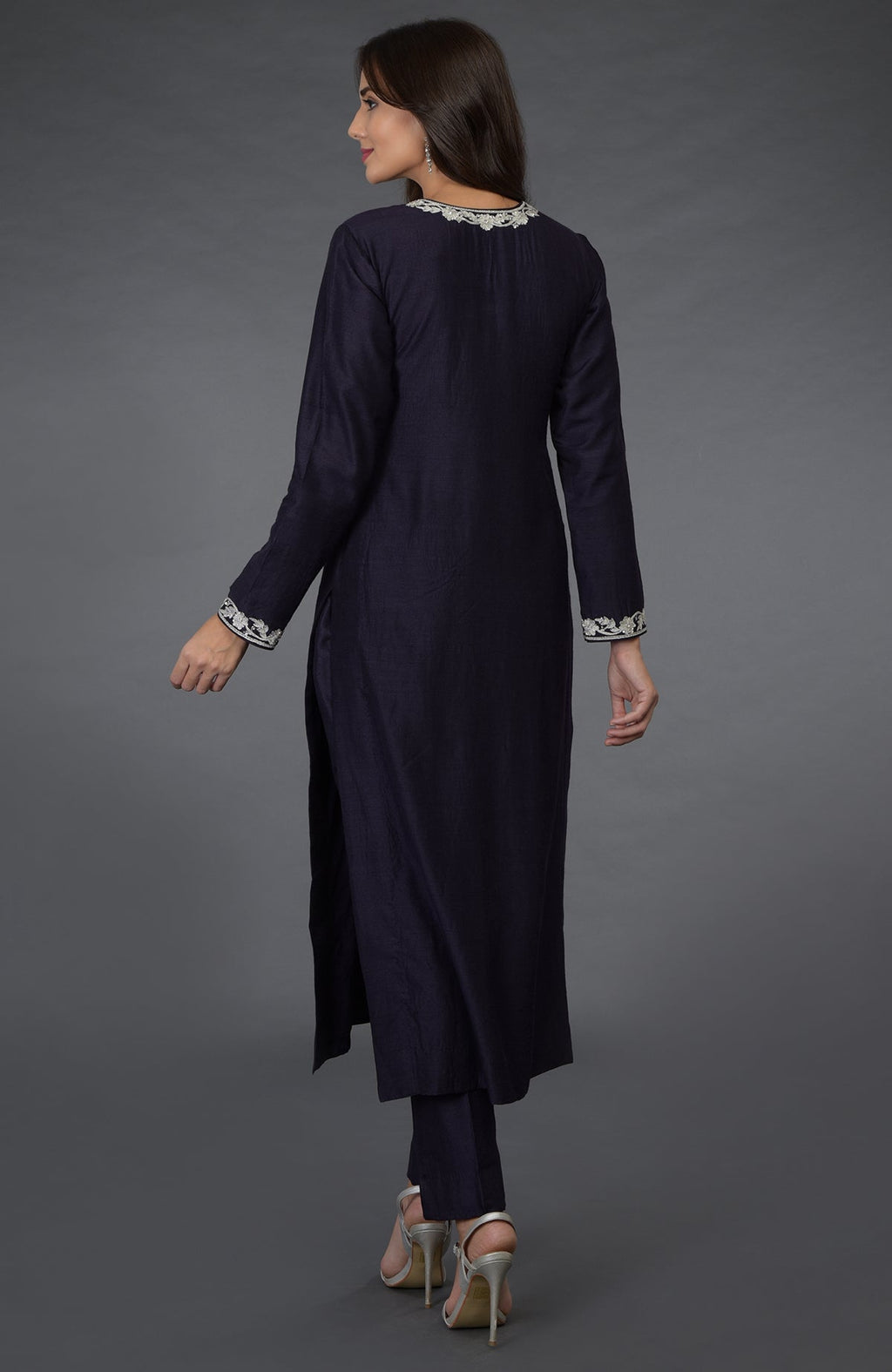 A woman from the back wearing an eclipse blue suit with silver embroidery and heels.