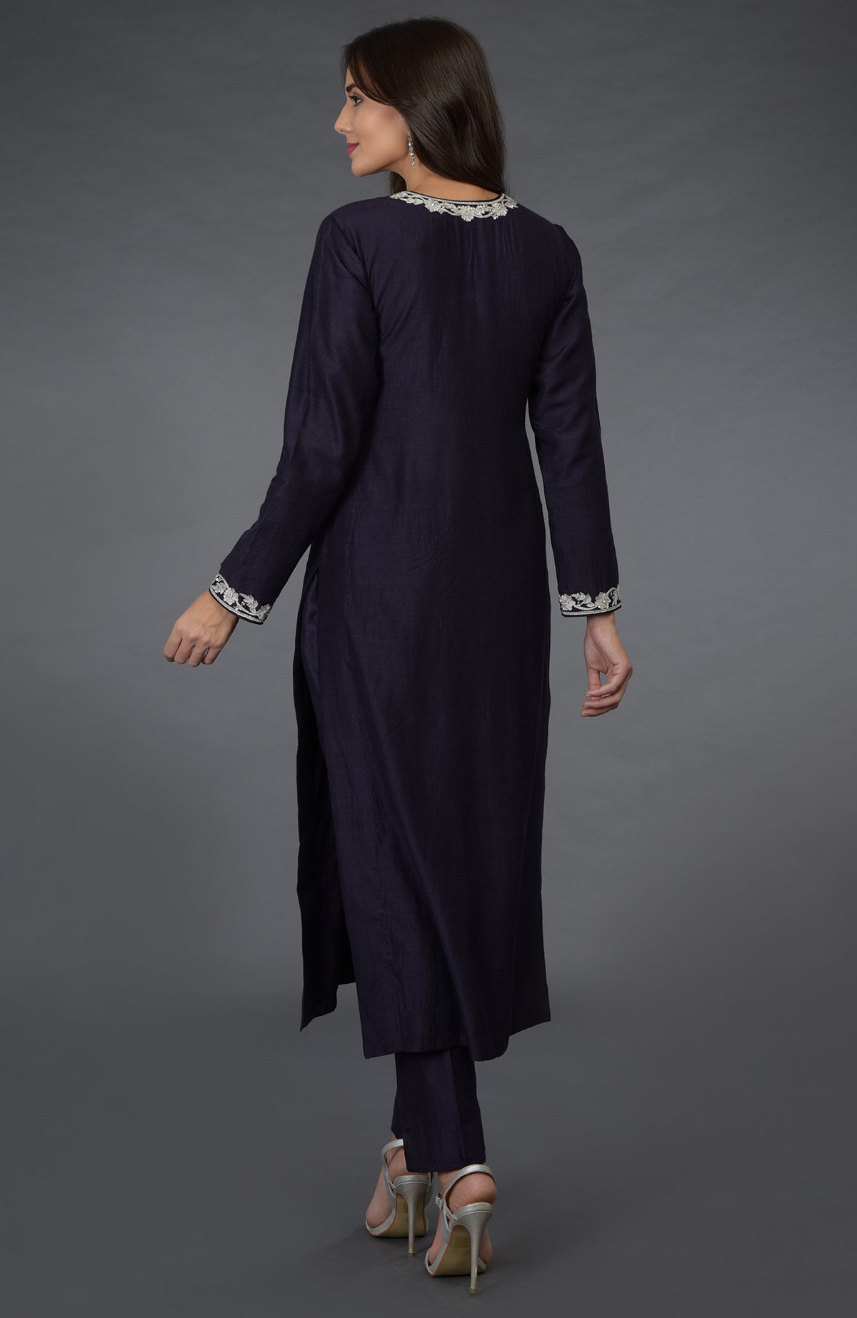 A woman from the back wearing an eclipse blue suit with silver embroidery and heels.