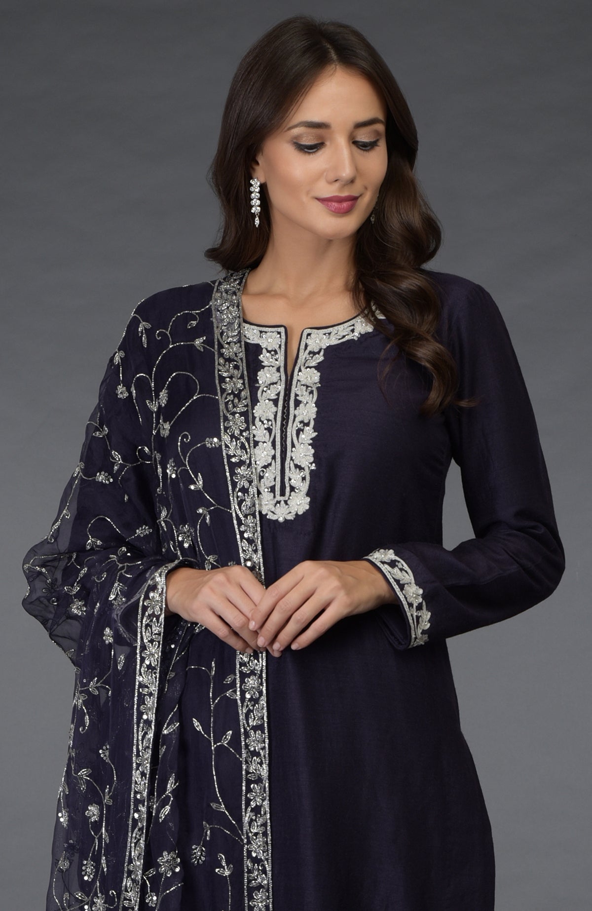 A woman models an eclipse blue suit with silver zari, beads, and sequin embroidery.
