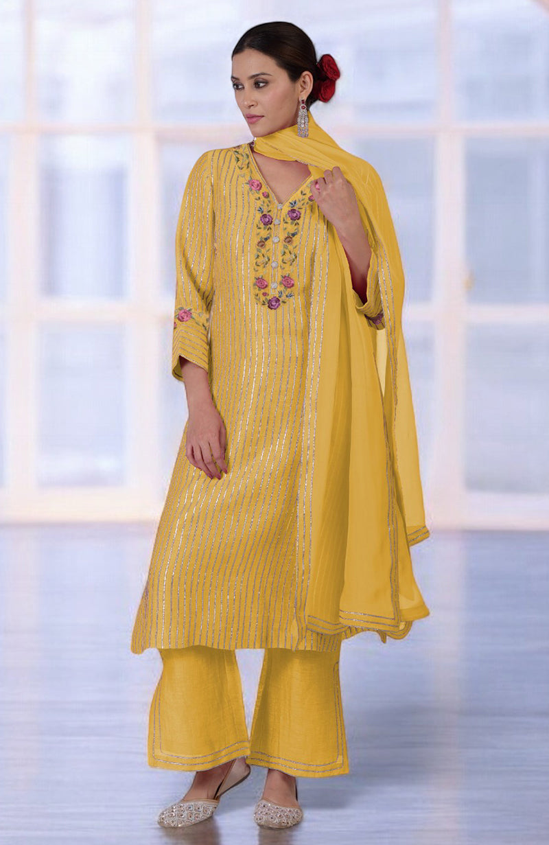 Woman in a yellow kurta set with silver stripes and floral embroidery.