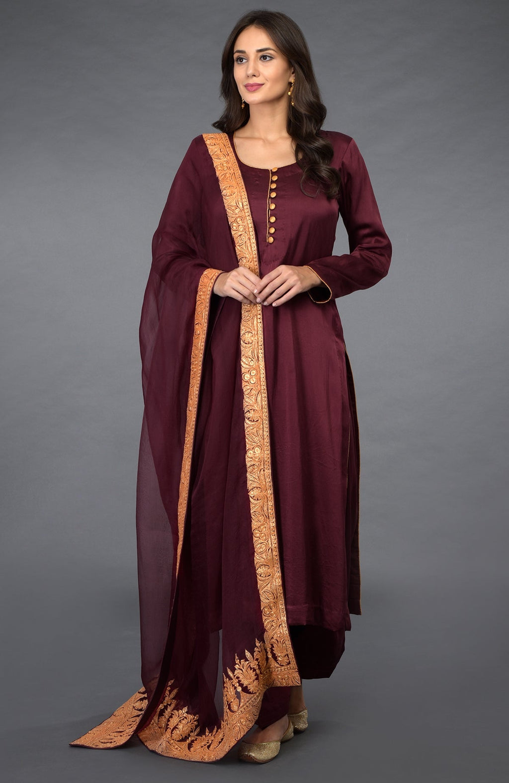 A woman models a burgundy salwar pants suit with gold embroidered dupatta.