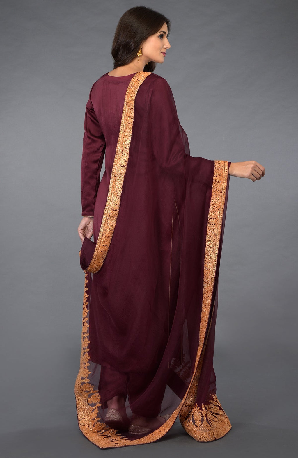Woman in a burgundy salwar suit with gold embroidered dupatta.