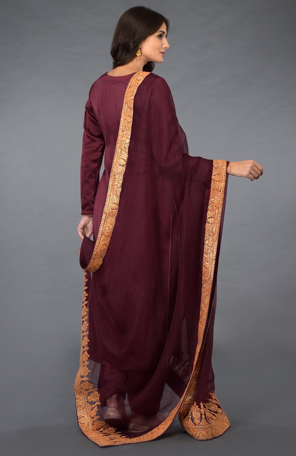 Woman in a burgundy salwar suit with gold embroidered dupatta.