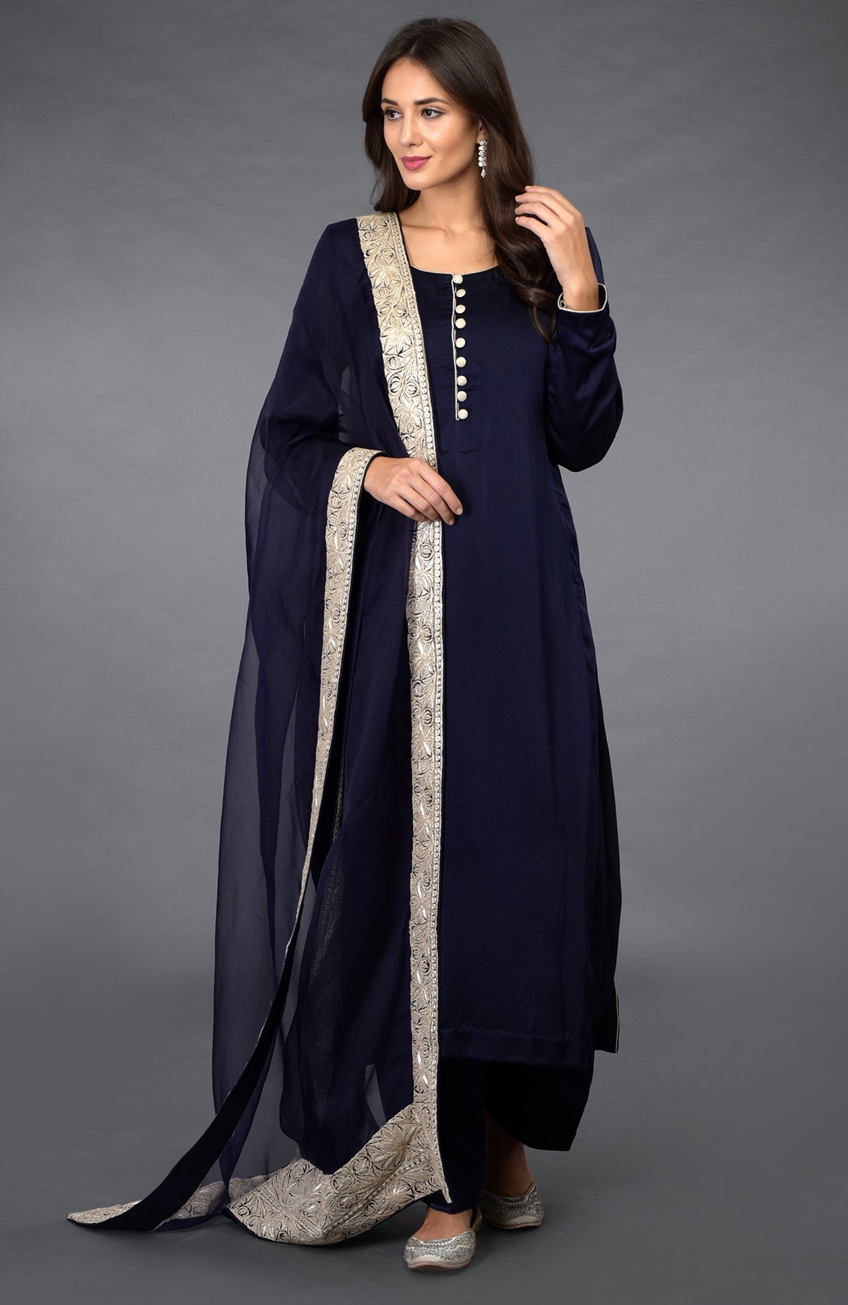 A woman models a midnight blue salwar pants suit with silver tilla embroidery.