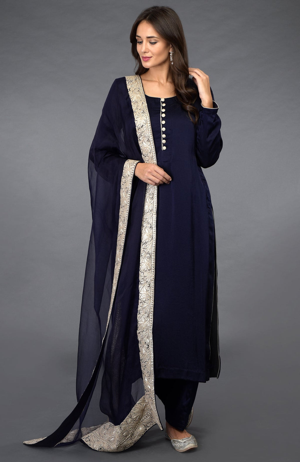 A woman models a midnight blue salwar pants suit with silver tilla embroidered dupatta.
