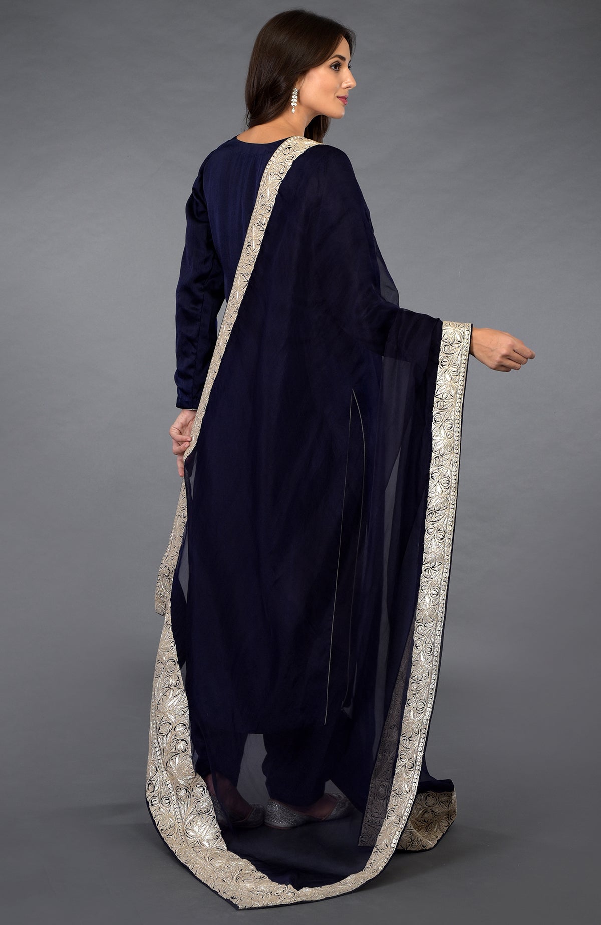 A woman in a midnight blue salwar suit with silver tilla embroidered dupatta.