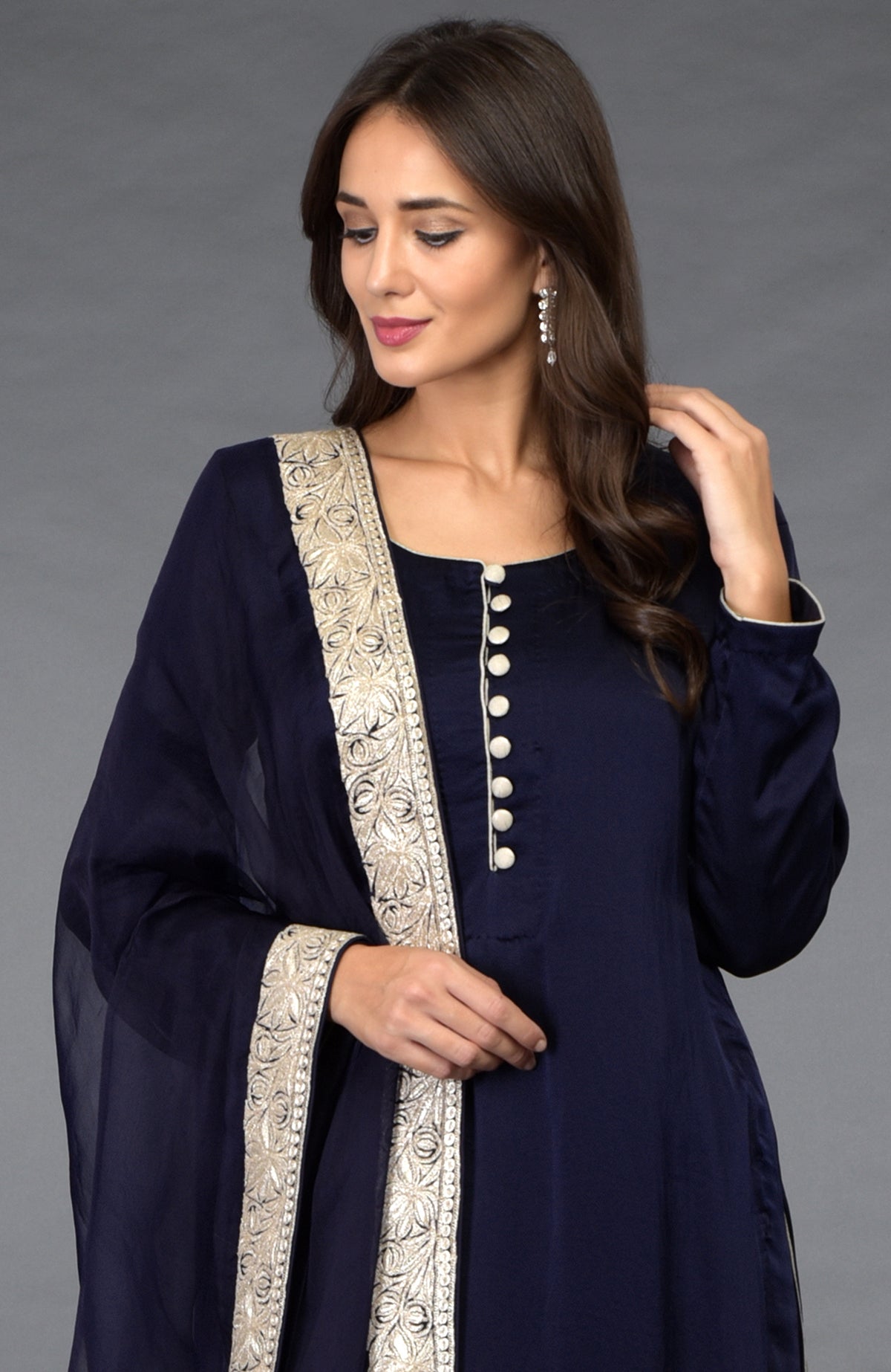 A woman models a midnight blue salwar pants suit with silver tilla embroidery.