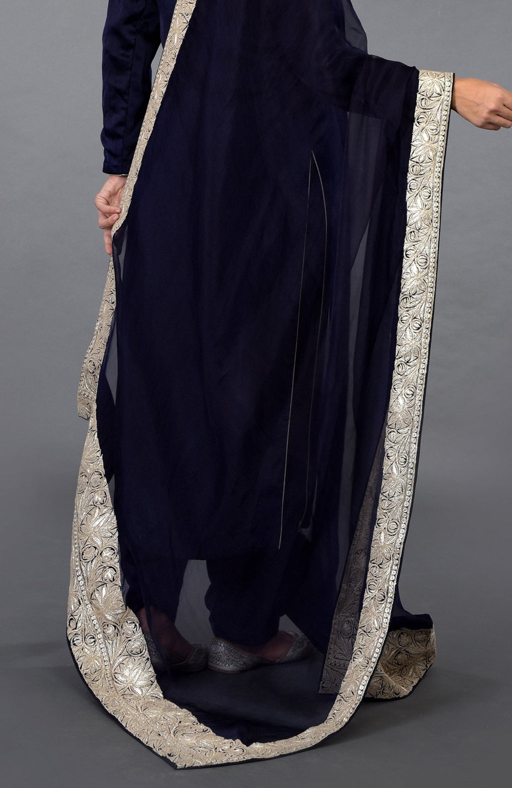 A person wearing a midnight blue salwar suit with a silver tilla embroidered dupatta.