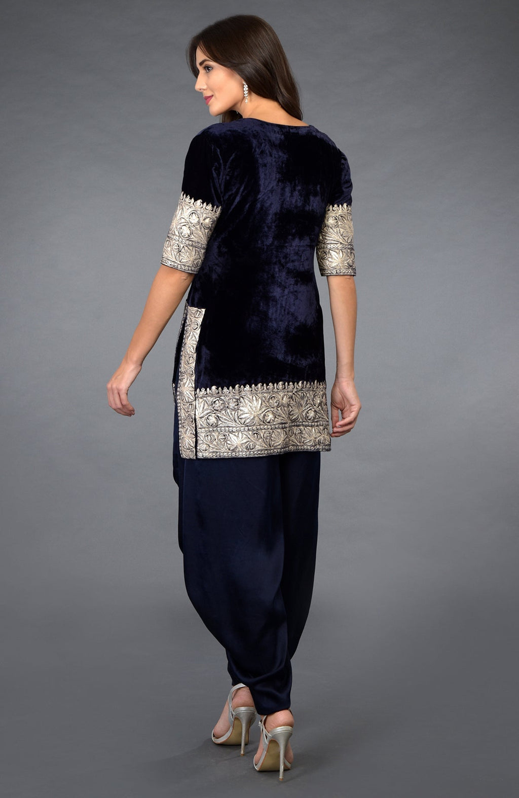 A woman models a midnight blue velvet dhoti pants suit with silver tilla embroidery.