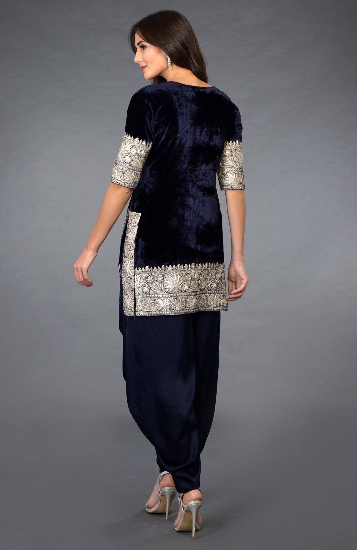 A woman models a midnight blue velvet dhoti pants suit with silver tilla embroidery.
