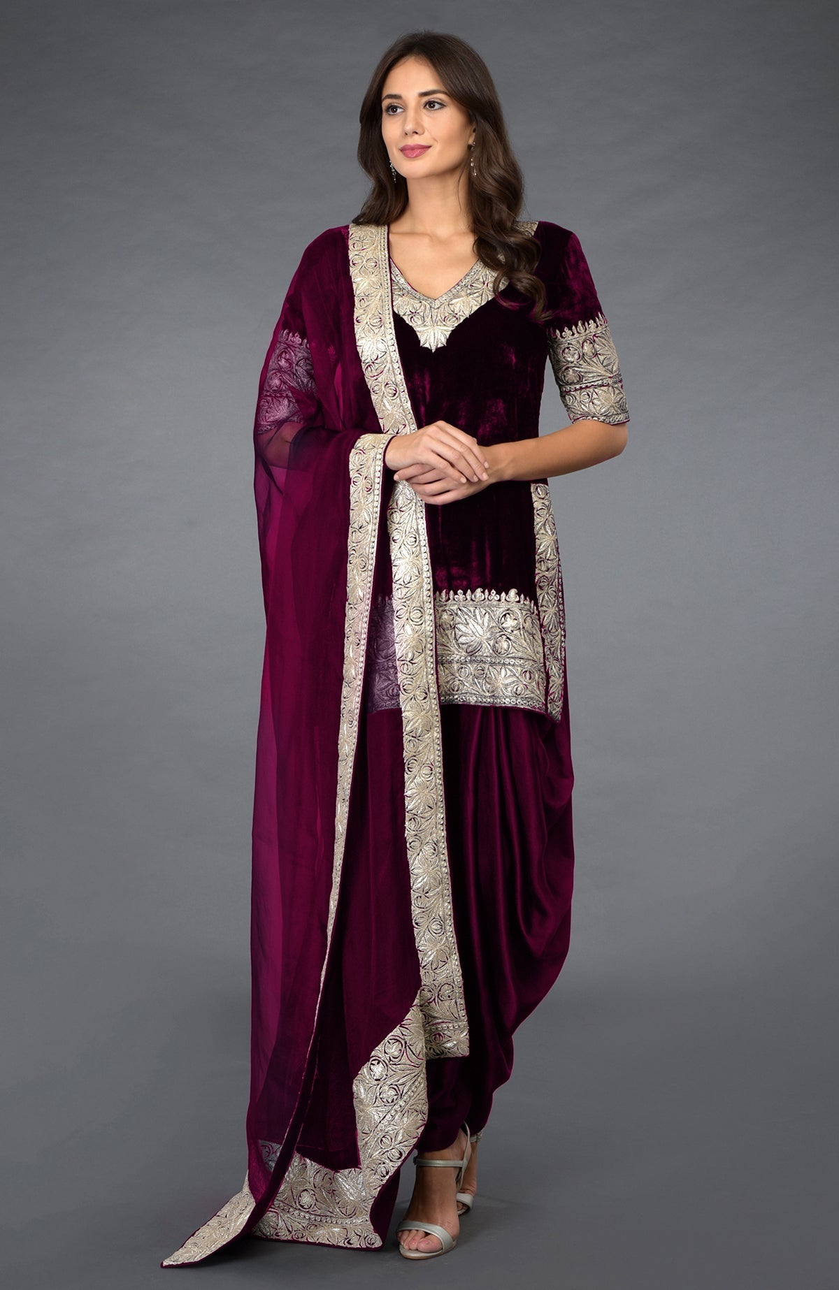 A woman models a mulled grape velvet dhoti pants suit with silver tilla embroidery.