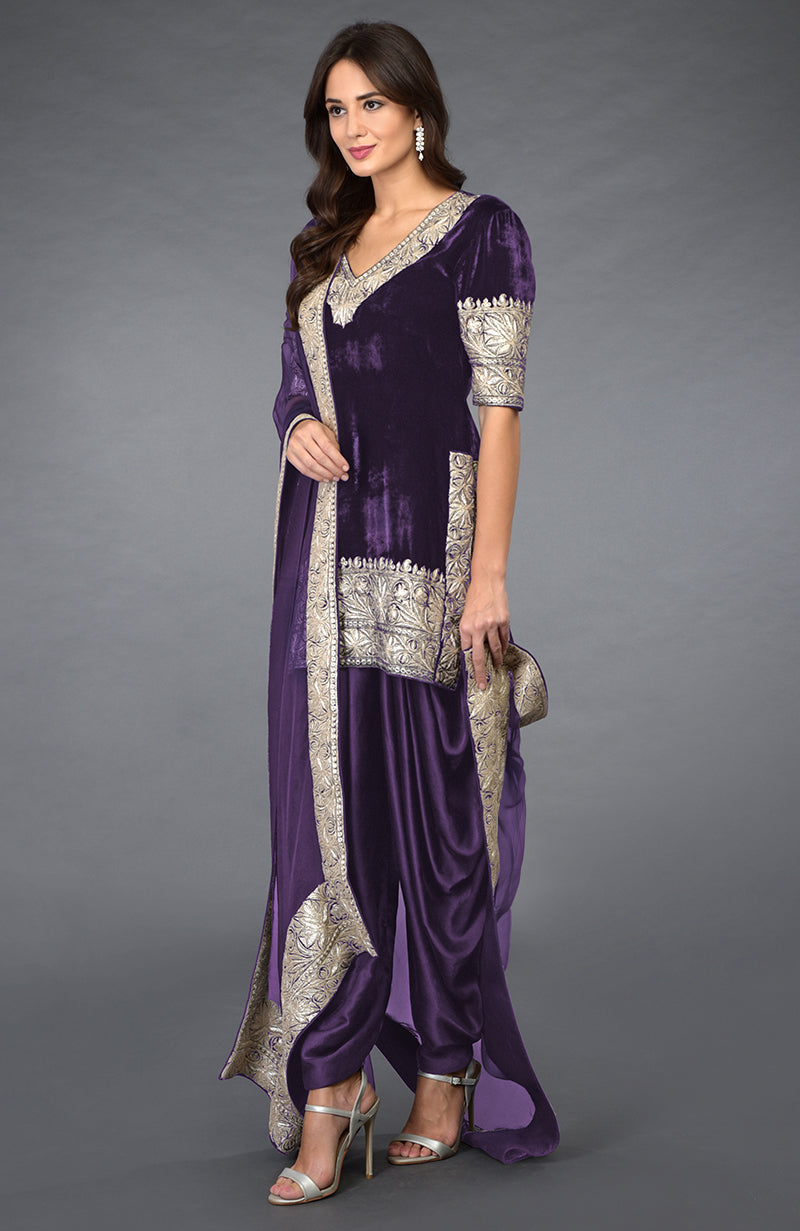 A woman models a purple velvet dhoti pants suit with silver tilla embroidery.