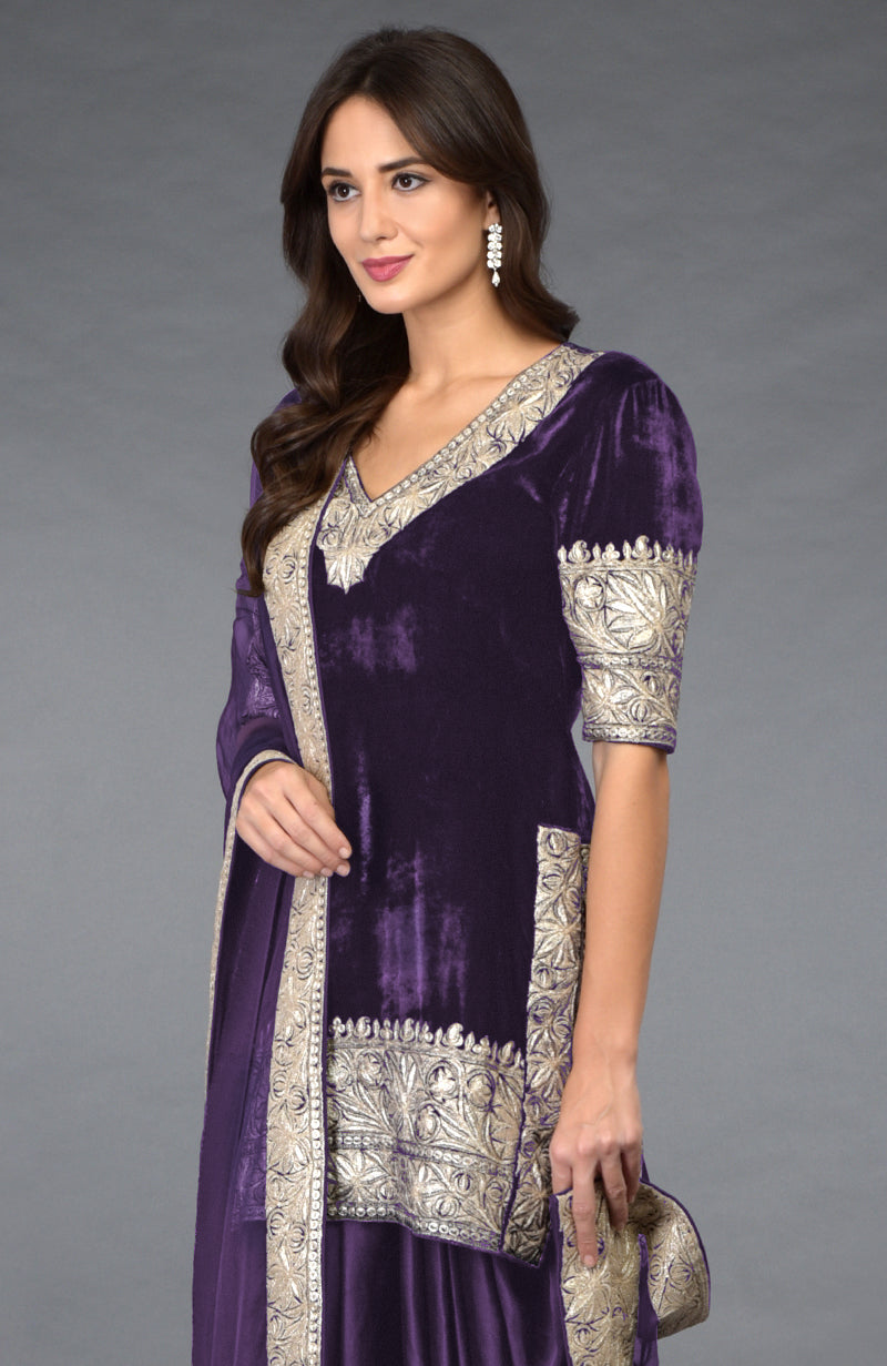A woman models a mulled grape velvet dhoti pants suit with silver tilla embroidery.