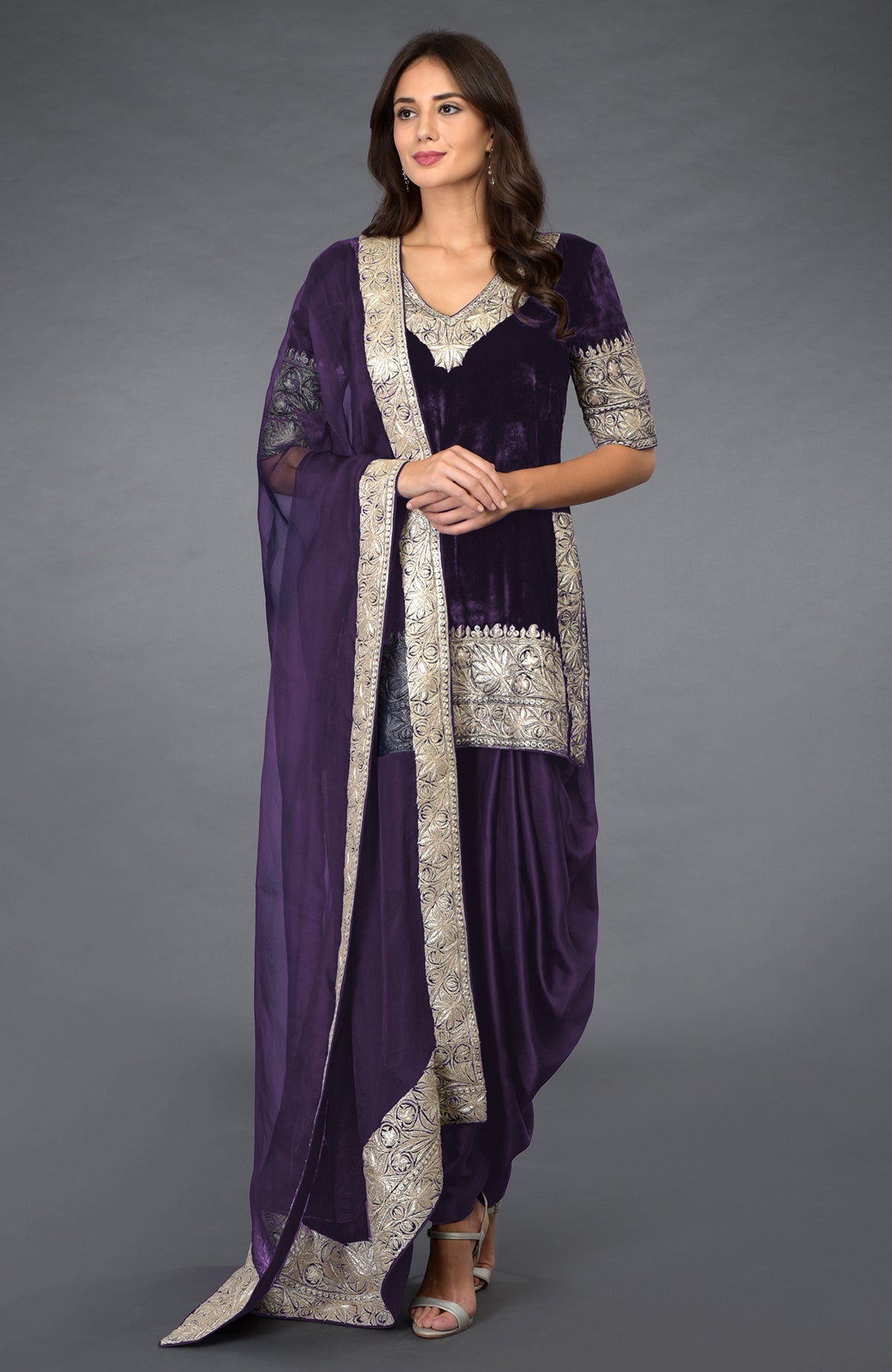 A woman models a mulled grape velvet dhoti pants suit with silver tilla embroidery.