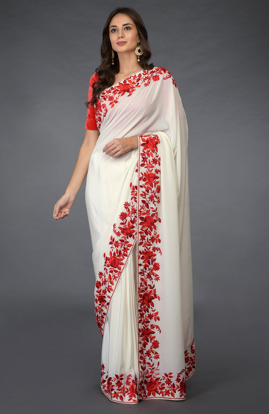 An elegant woman models an ivory saree with red floral Parsi Gara embroidery.