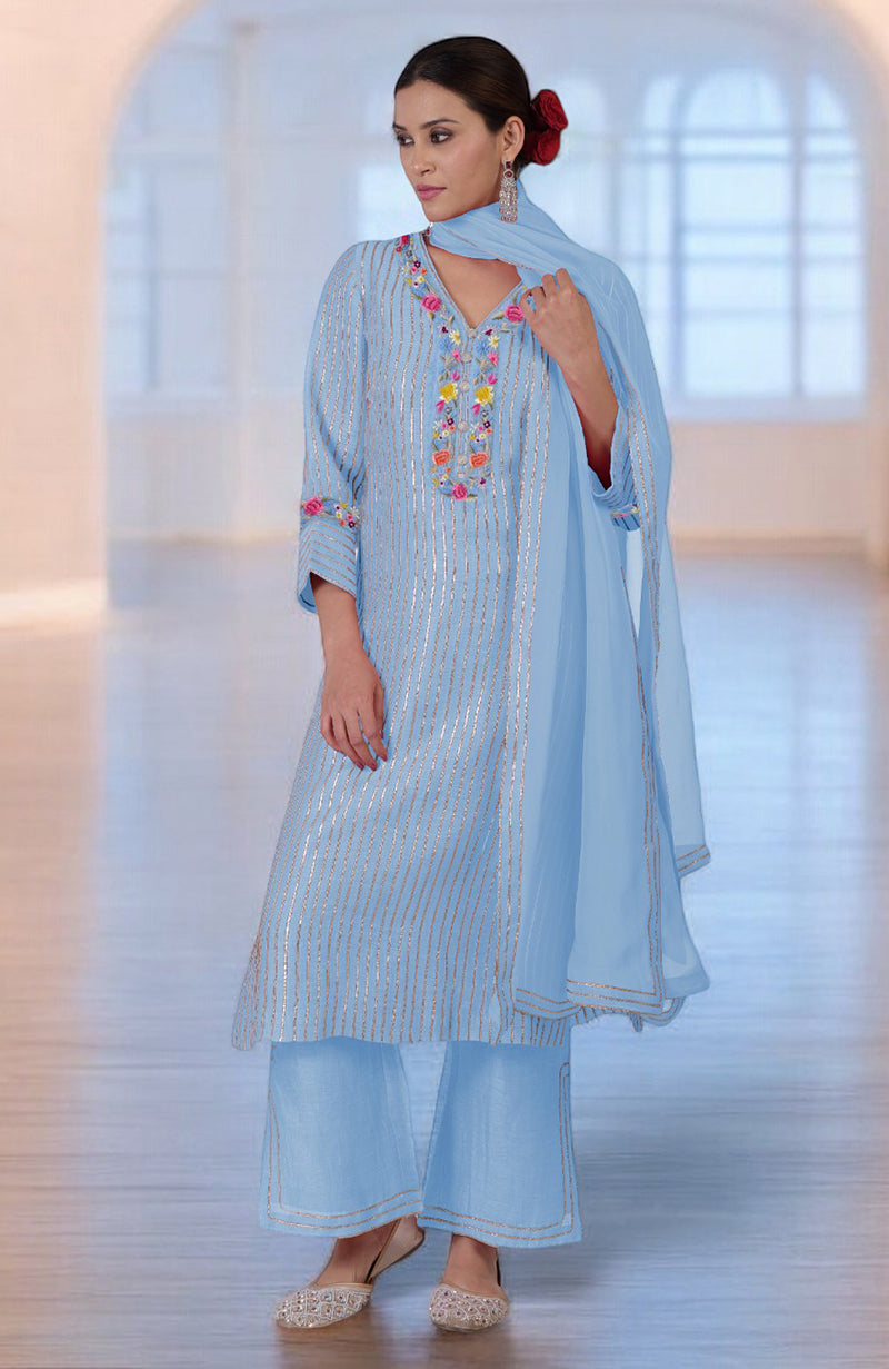 A woman models a light blue kurta set with gold stripes and colorful embroidery.