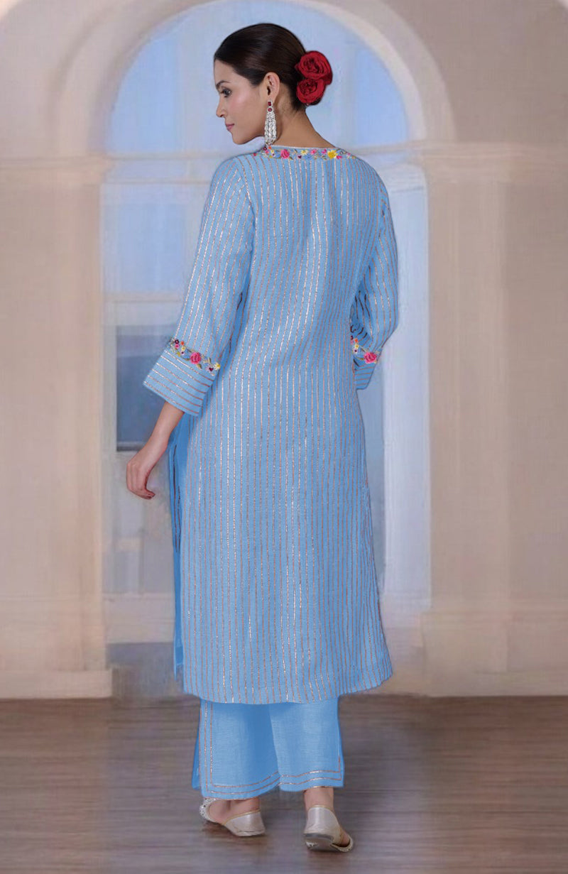 A woman models a cerulean blue silk linen suit with gota and Parsi Gara embroidery.