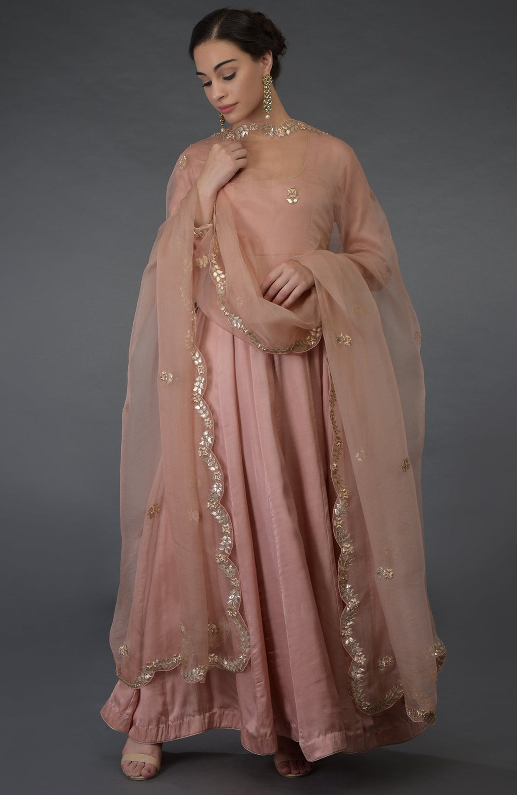 A woman models a pressed rose gota patti and zardozi hand-embroidered suit.