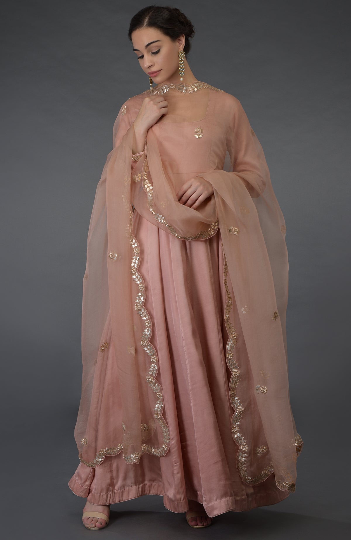 A woman models a pressed rose gota patti and zardozi hand-embroidered suit.