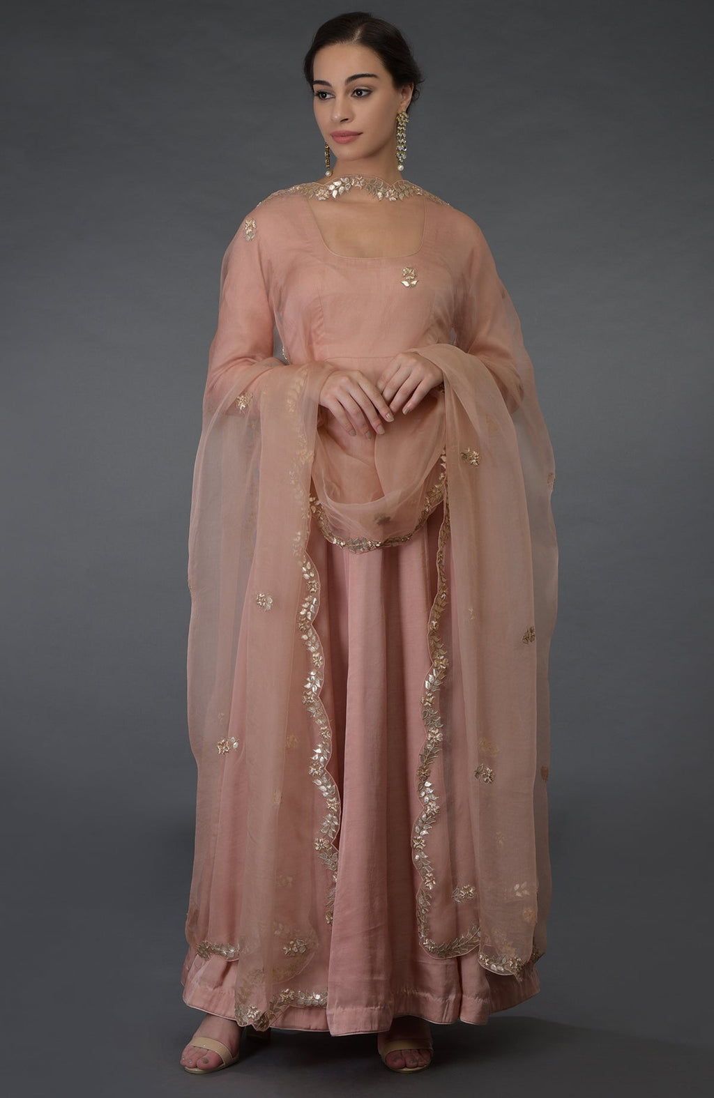 A woman models a pressed rose gota patti and zardozi hand-embroidered suit.