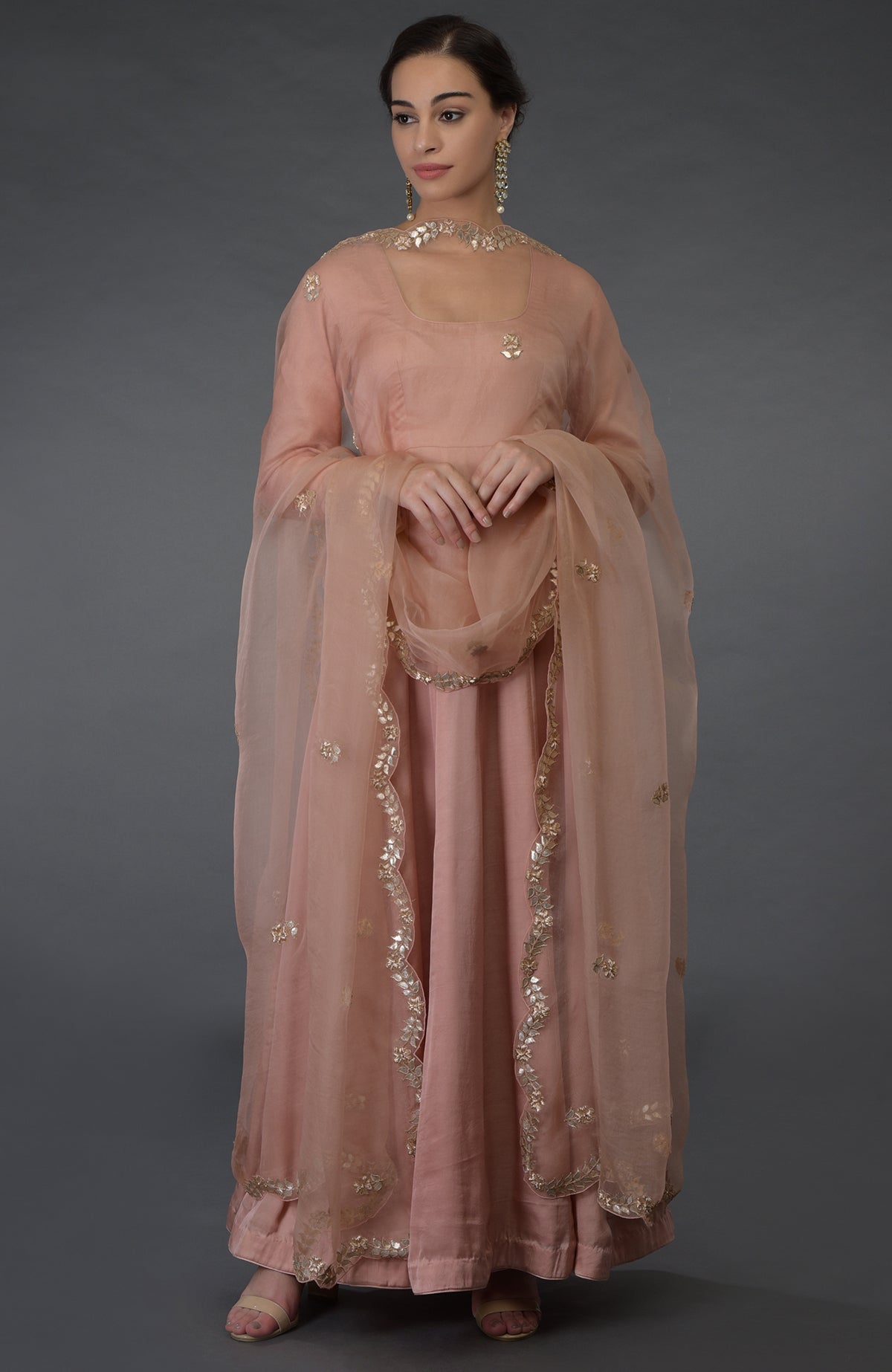 A woman models a pressed rose gota patti and zardozi hand-embroidered suit.
