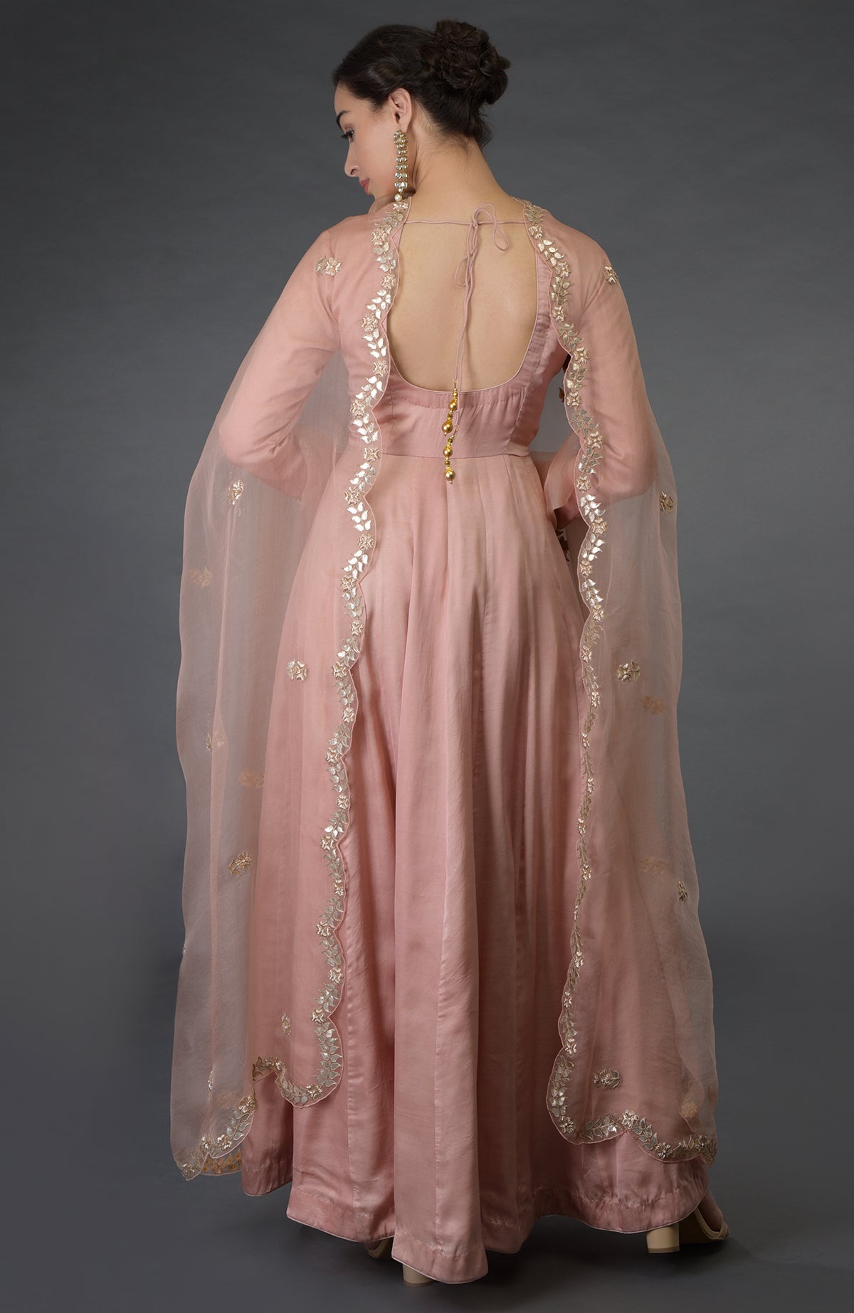 A woman models a pressed rose gota patti and zardozi hand-embroidered suit.