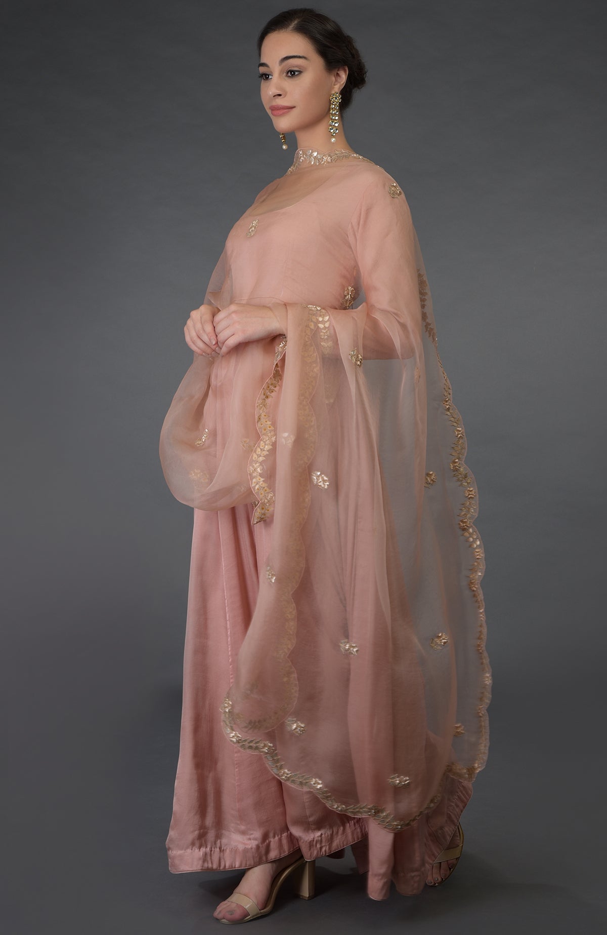 A woman models a pressed rose gota patti and zardozi hand-embroidered suit.
