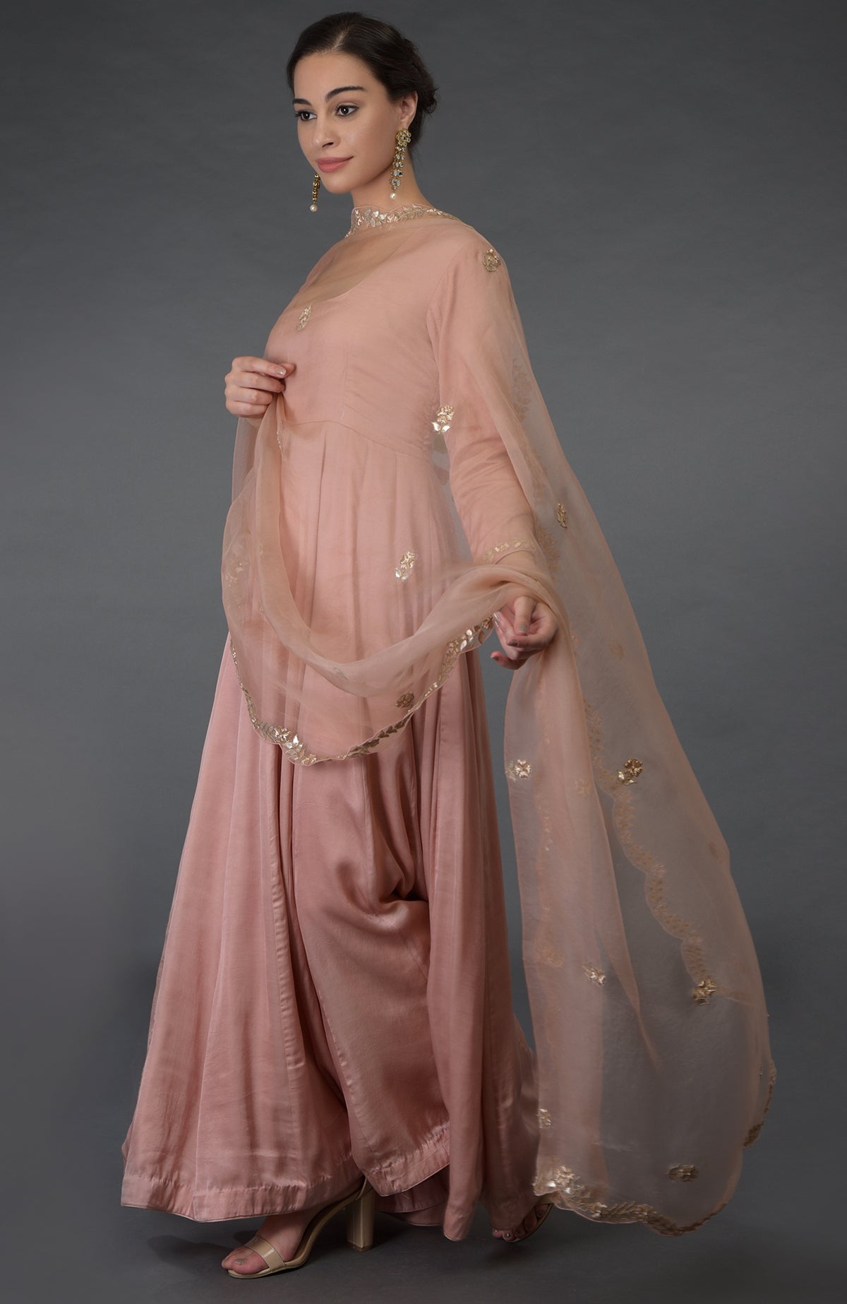 A woman models a pressed rose gota patti and zardozi hand-embroidered suit.