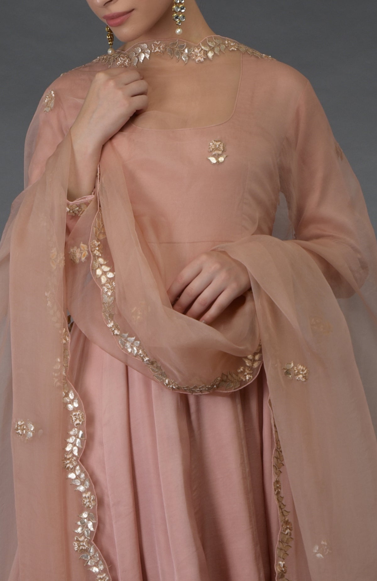 A woman models a pressed rose gota patti and zardozi hand-embroidered suit.