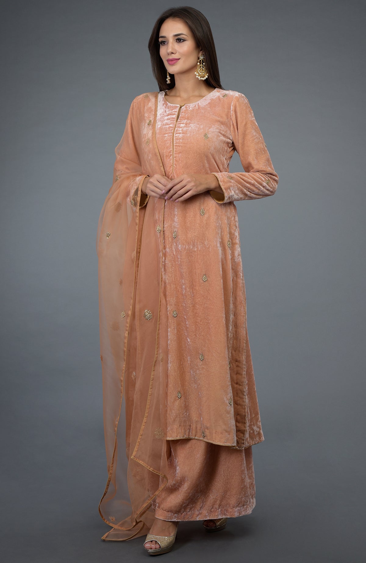 A woman models a peach rose zardozi hand embroidered silk velvet suit.