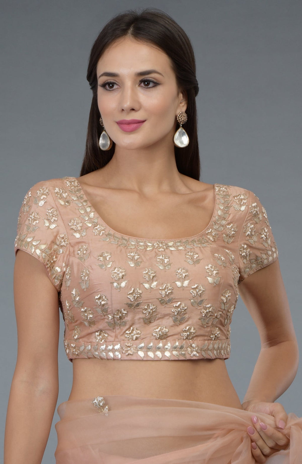 A woman models a pressed rose silk blouse with zardozi and gota patti embroidery.