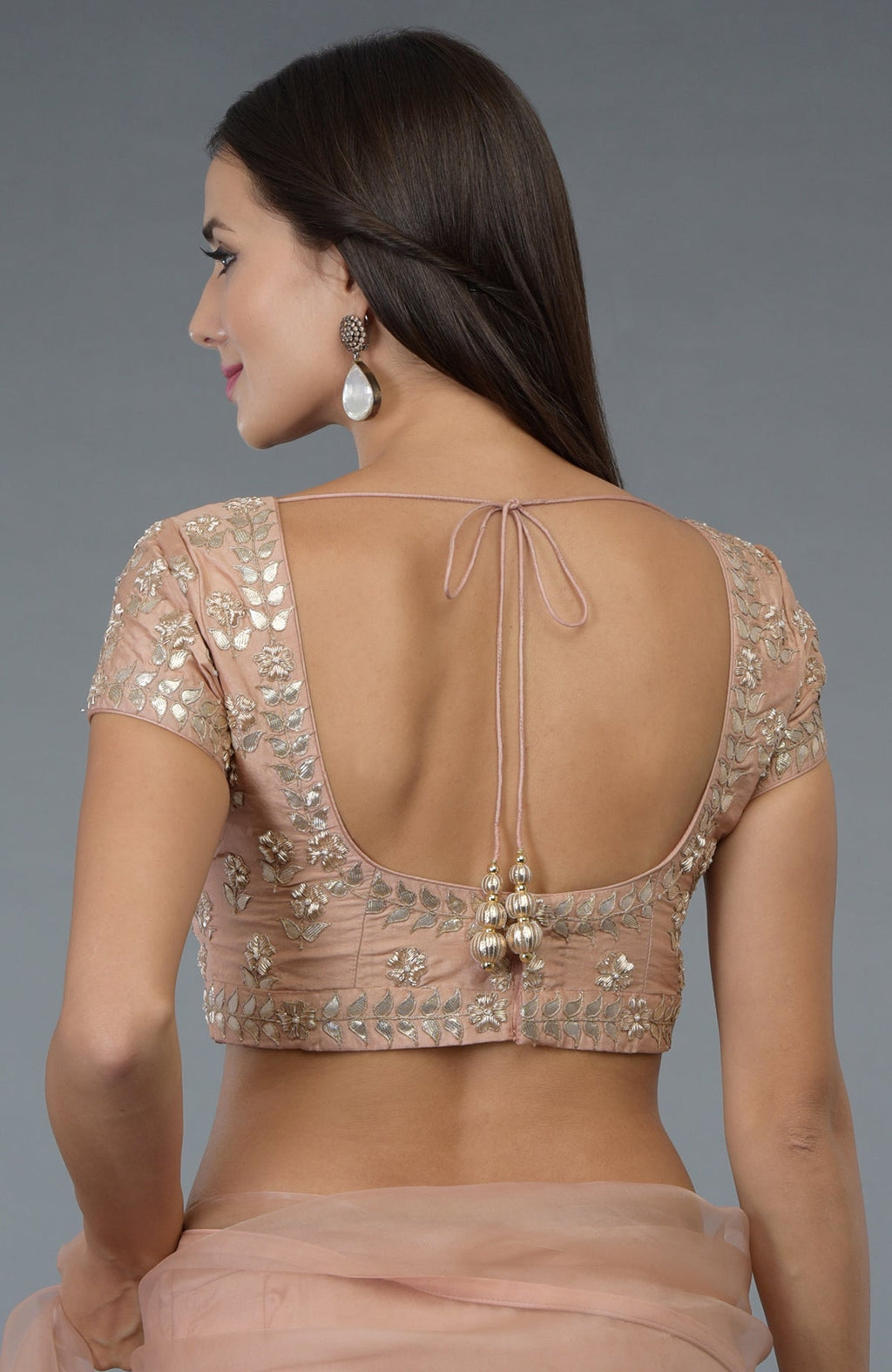 A woman models a pressed rose silk blouse with zardozi and gota patti embroidery.
