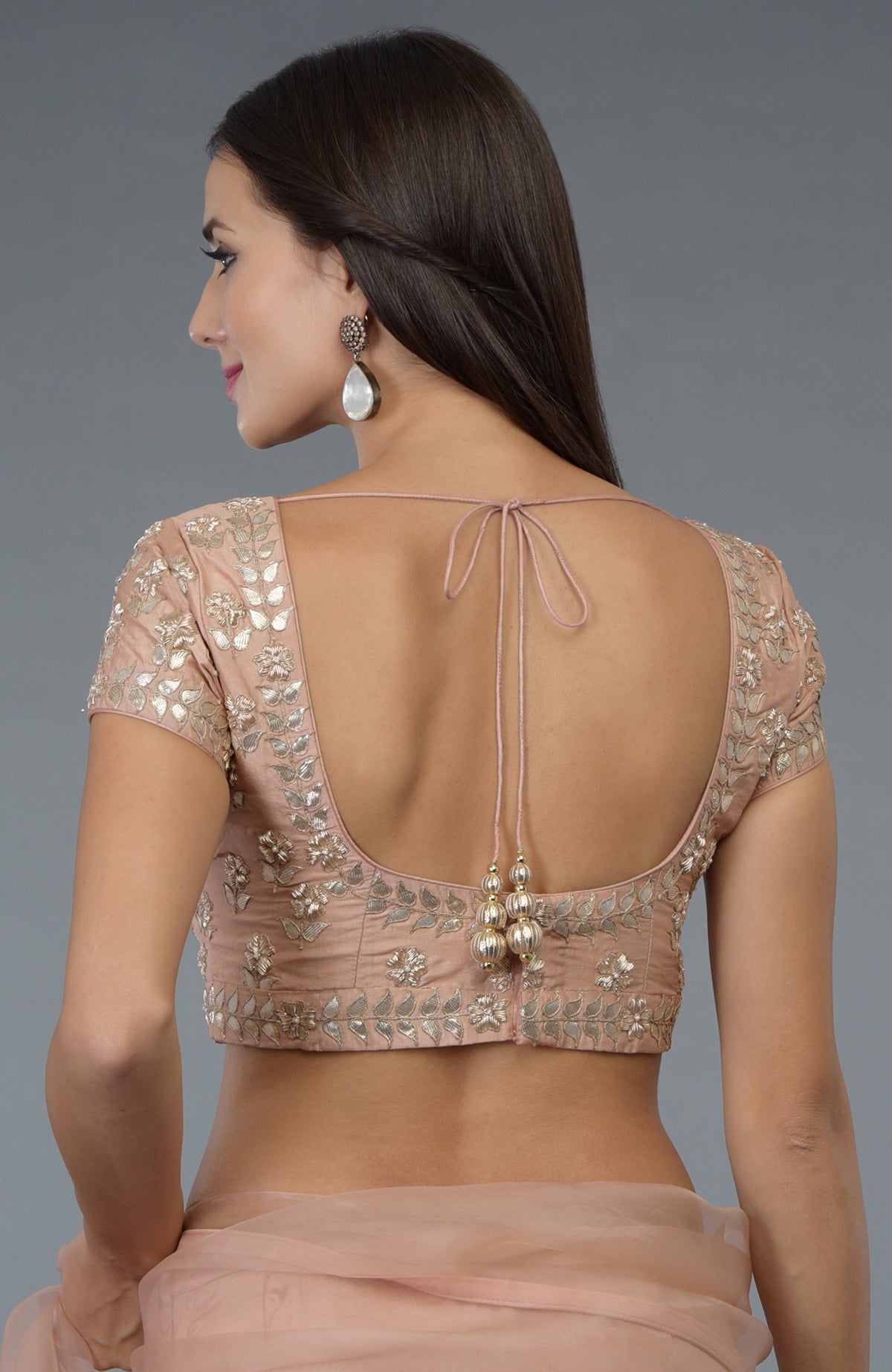 A woman models a pressed rose silk blouse with zardozi and gota patti embroidery.