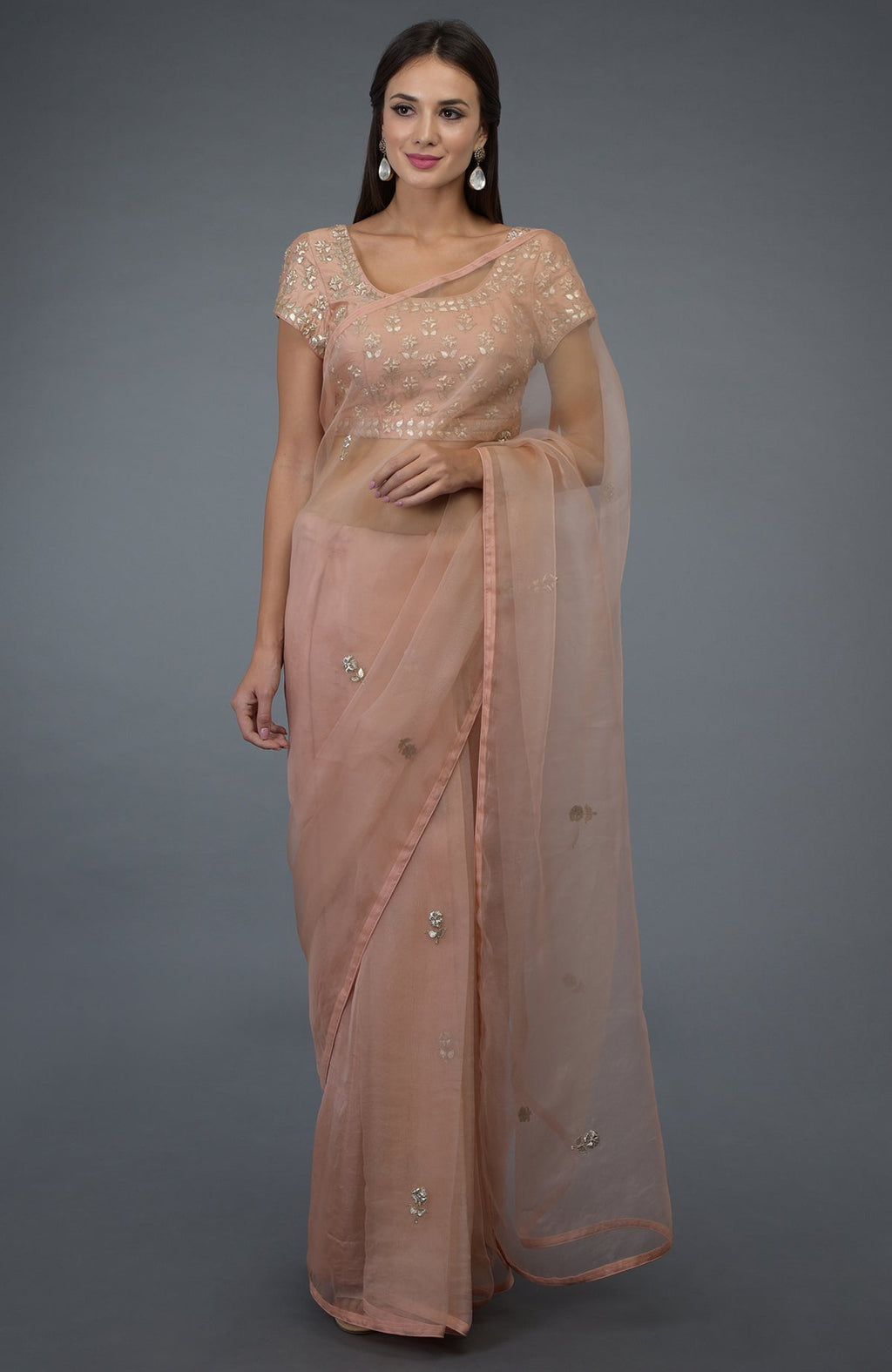 A woman models a pressed rose organza silk saree with zardozi and gota patti embroidery.