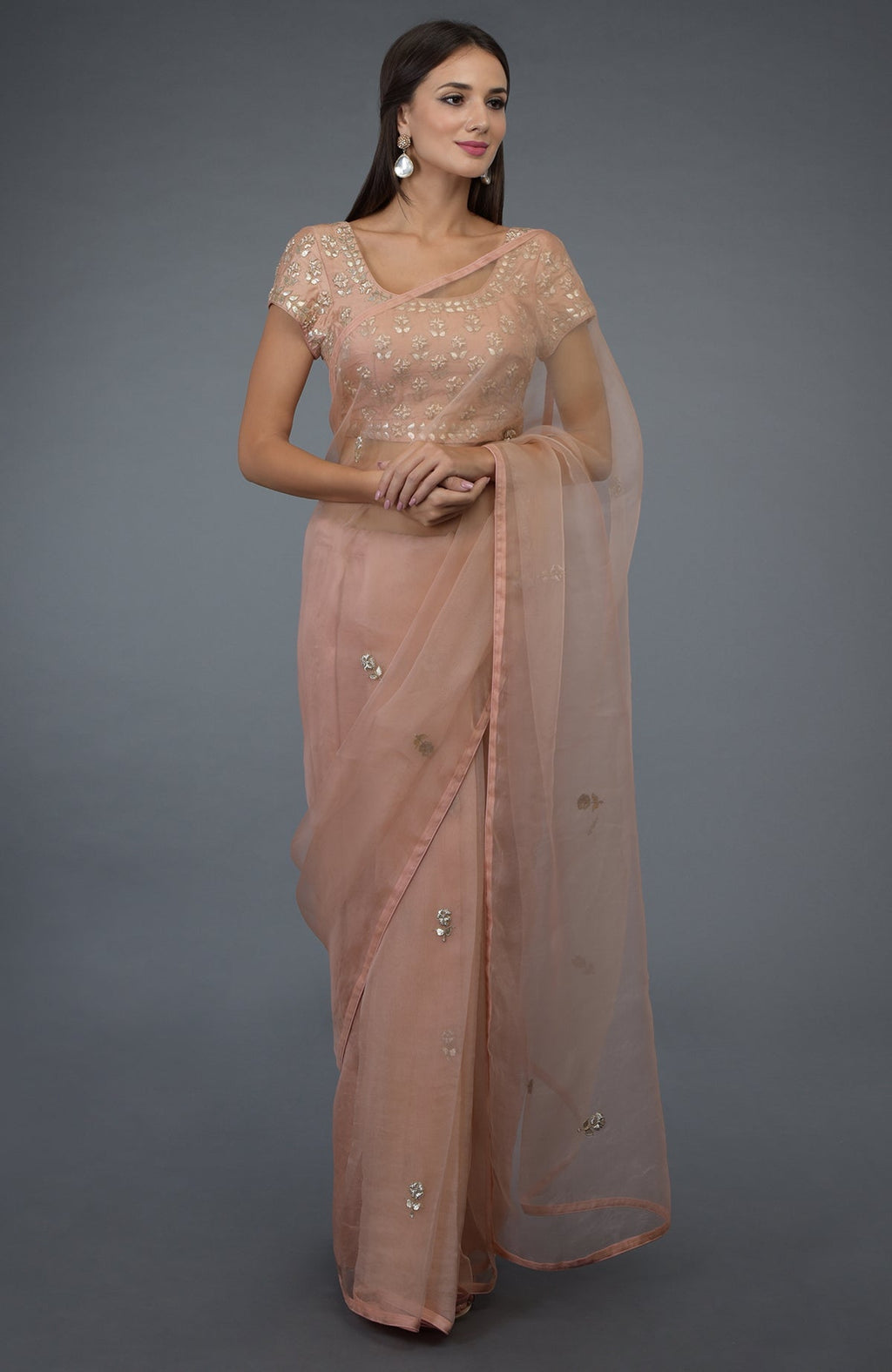 A woman models a pressed rose organza silk saree with zardozi and gota patti embroidery.