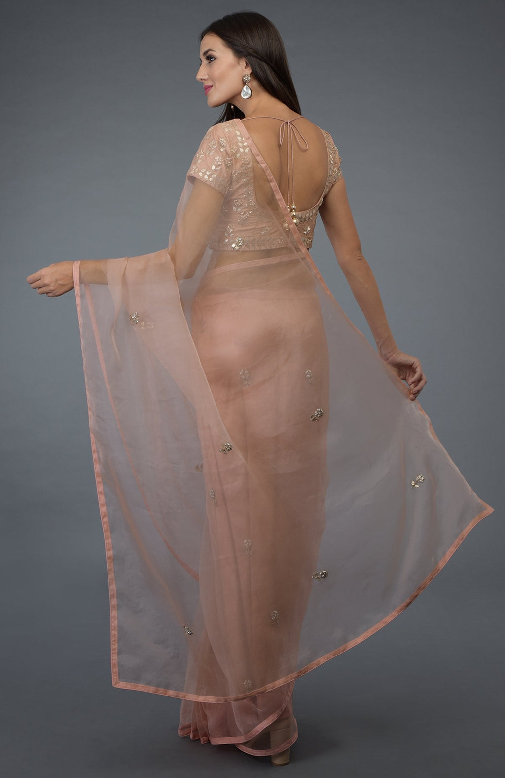 A woman models a pressed rose organza silk saree with a matching embroidered blouse.