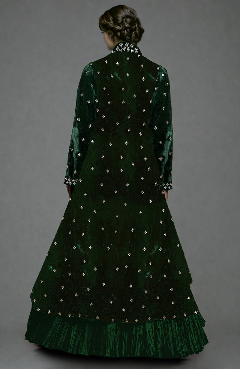 A woman from behind wears an emerald green velvet jacket with crystal embroidery and a tiered skirt.